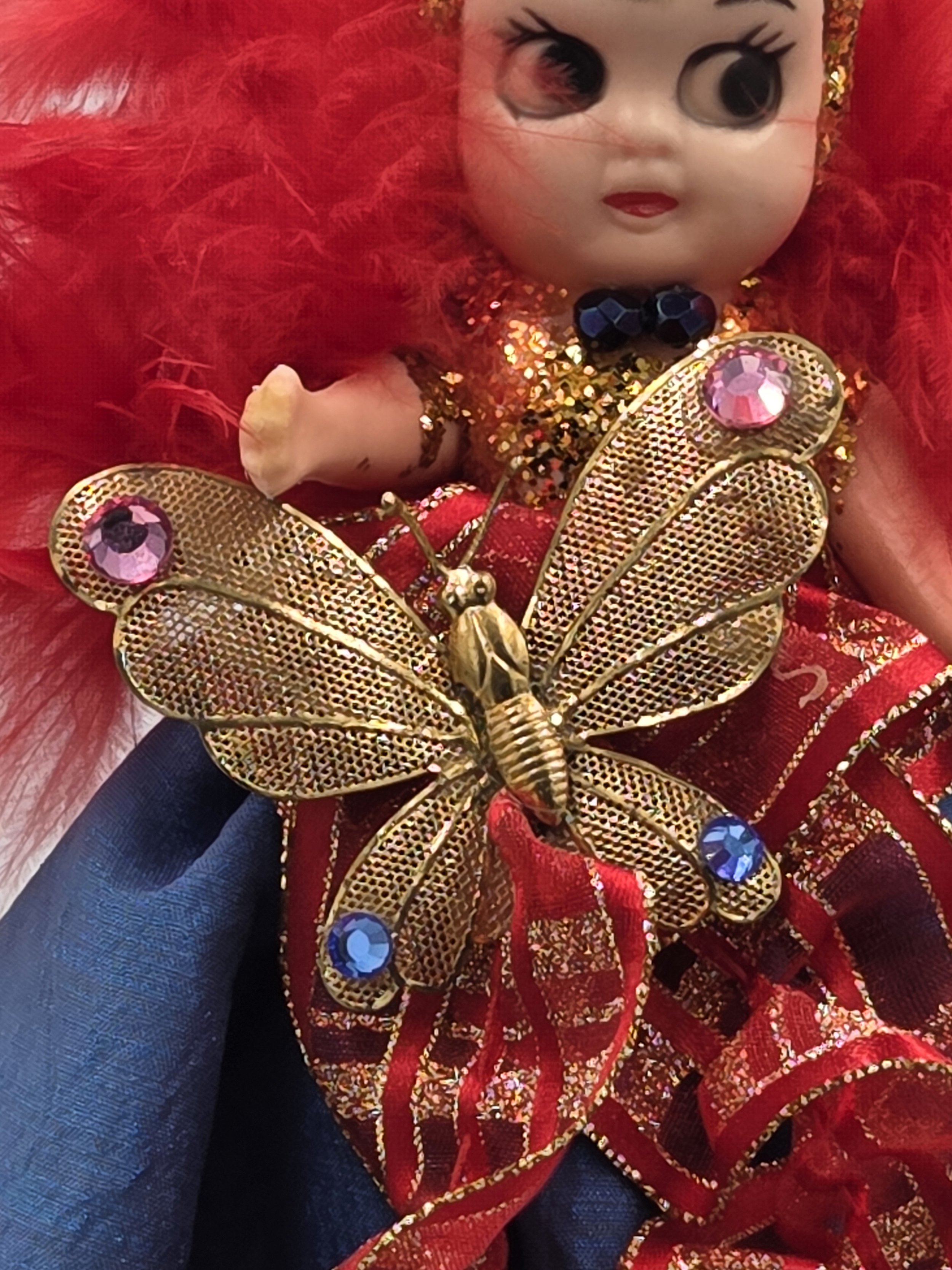 Close-up of golden metal butterfly with pink and blue glass stones.