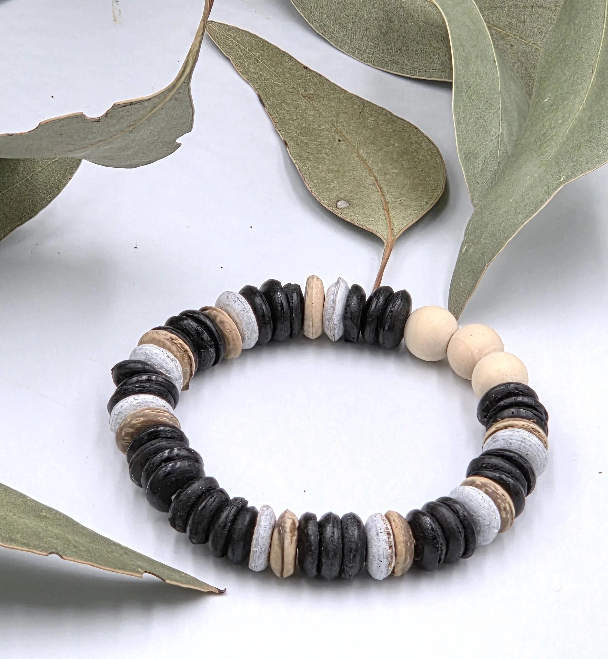 Striped brown and white coconut disc bracelet with three natural raw wood beads as a central focal point.