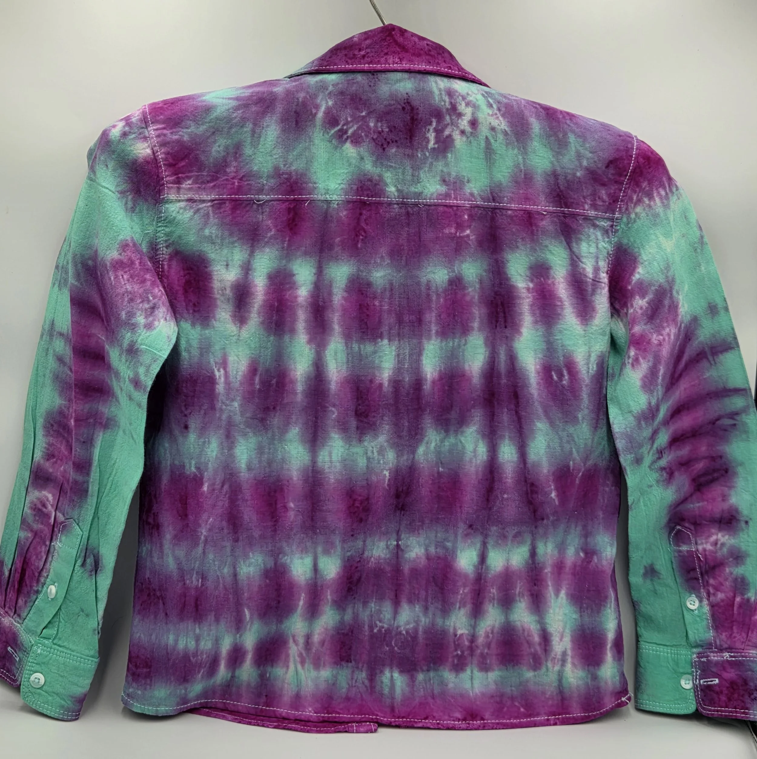 A child's size 6 long-sleeved collared shirt featuring a tie-dye pattern of consistent horizontal purple lines over a bright teal background.