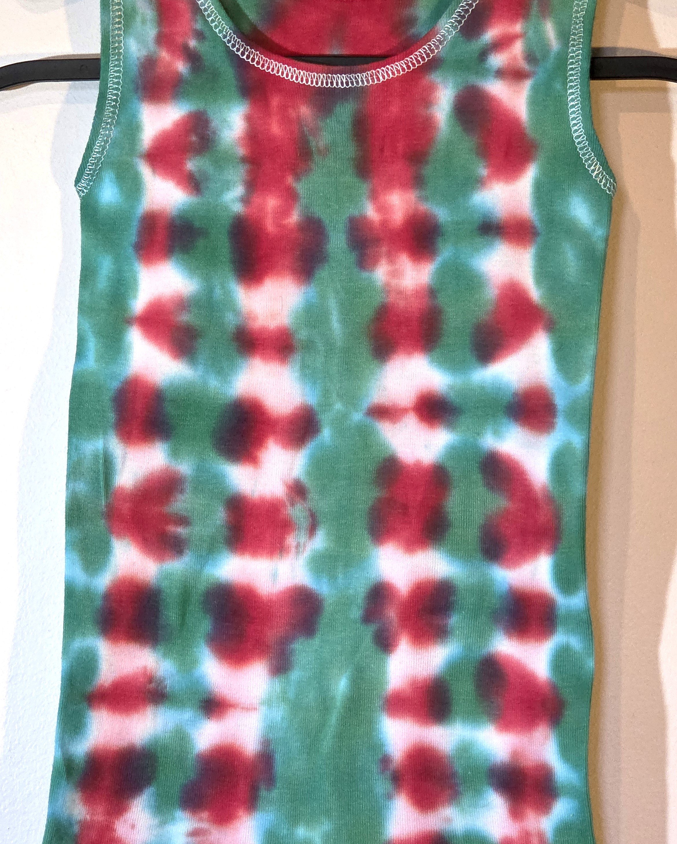 A child's singlet featuring a bold vertical tie-dye pattern of green and red columns with striking white patches down the red sections.