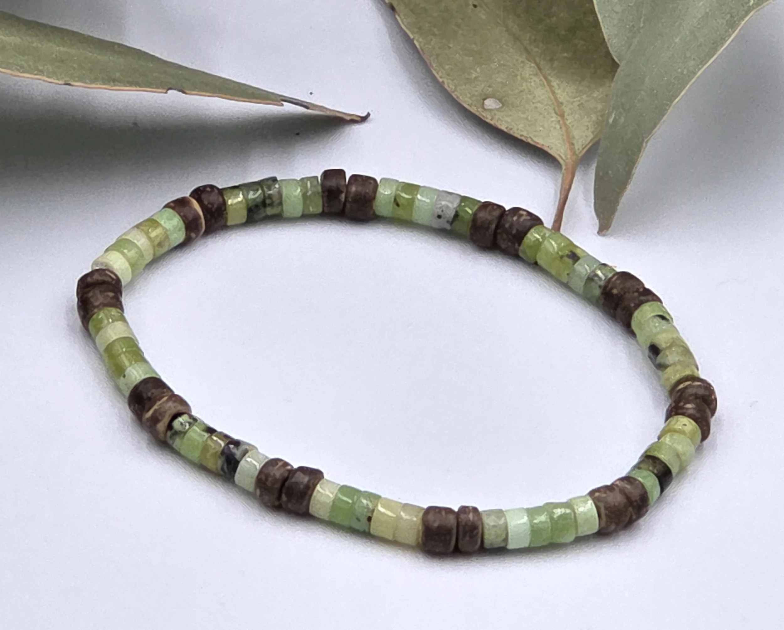 Very small green chrysoprase discs alternating in groups of five with pairs of brown coconut discs on a delicate elastic bracelet.