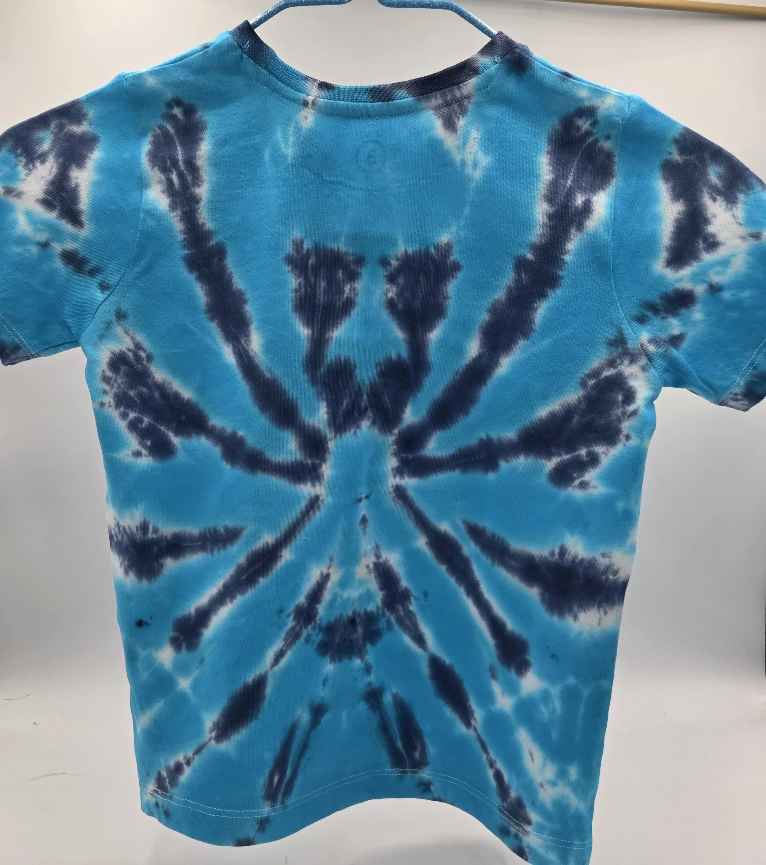 child size 3 cotton t-shirt featuring a dark blue tie-dye spider pattern against a bright turquoise background.
