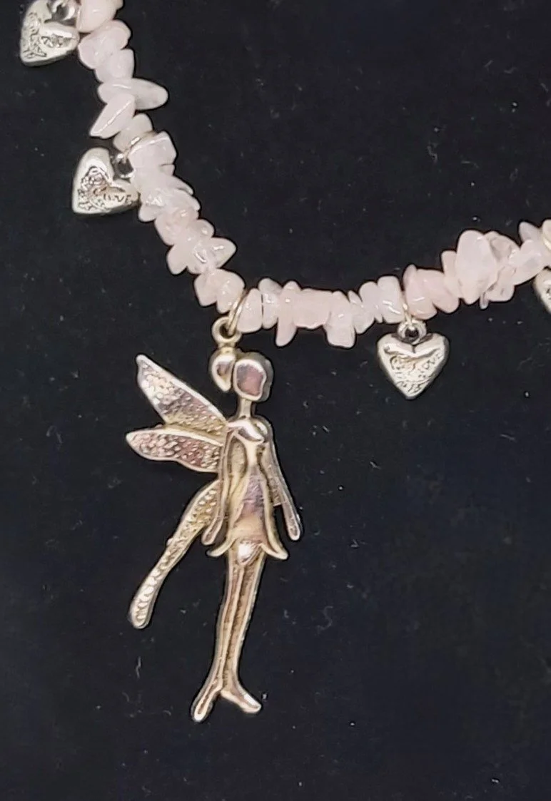 close up of A 44cm choker style necklace of genuine rose quartz chips with silver love hearts and a large silver fairy charm