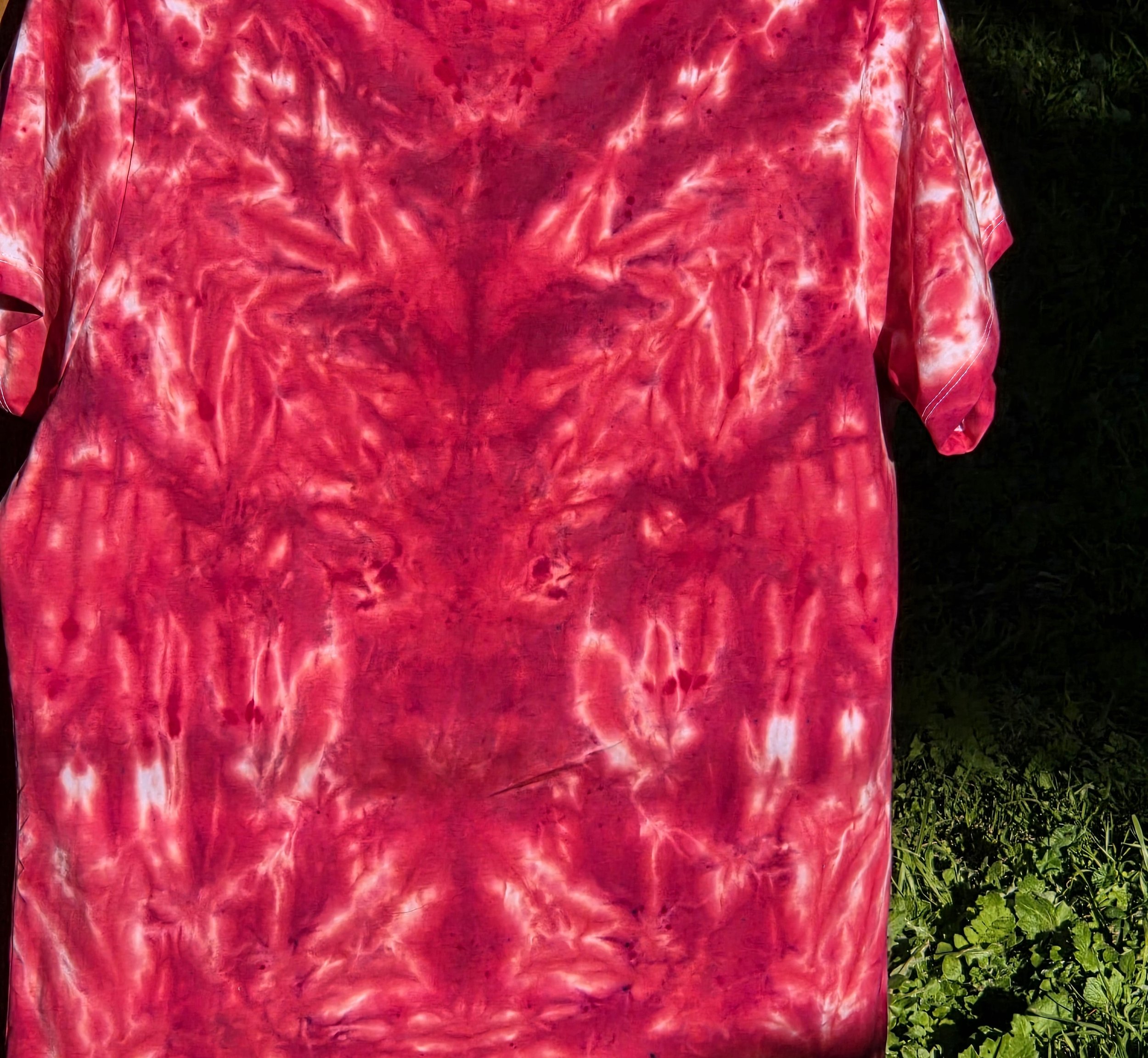 back view of A size 14 women's t-shirt featuring a highly saturated red and coral tie-dye pattern of abstract swirls radiating from the center.