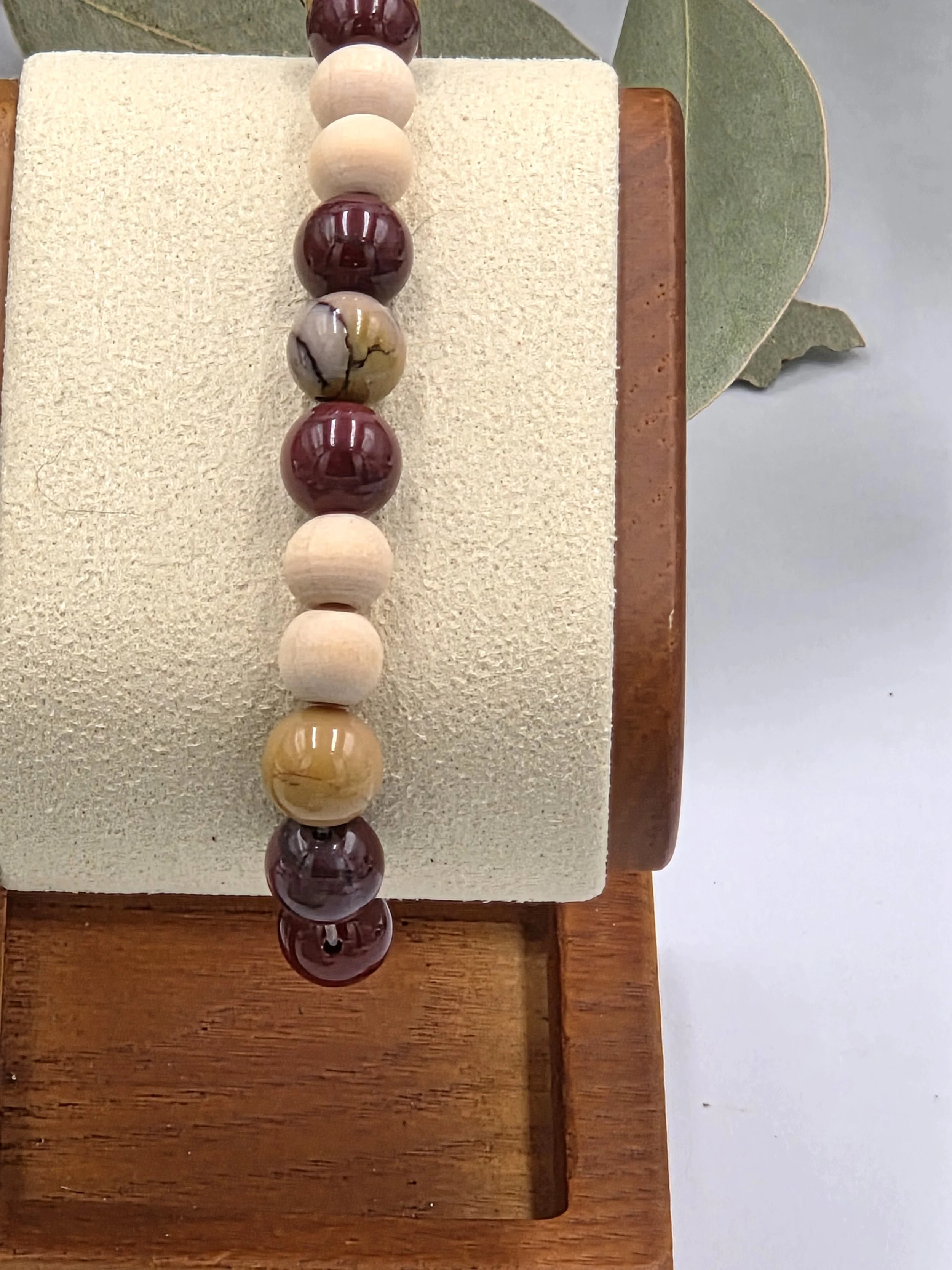 Earthy red and yellow Mookaite jasper beads alternating with small natural wood beads on an elastic bracelet.