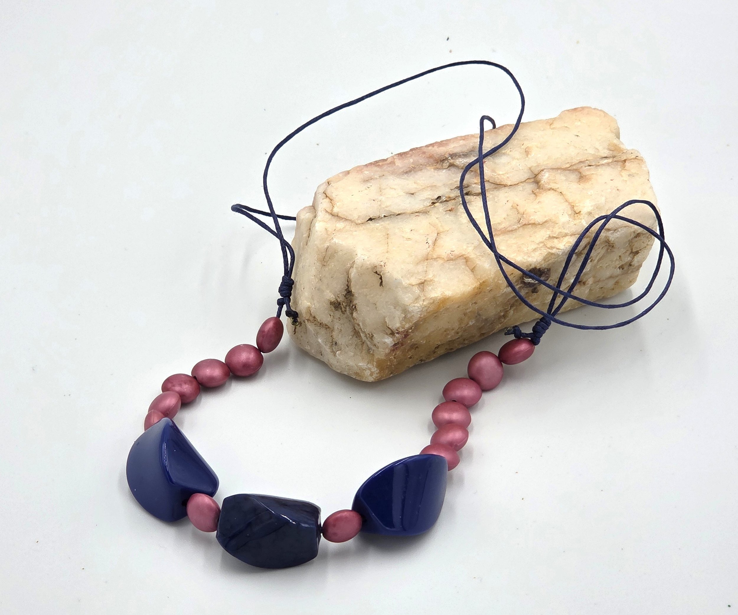 Navy blue twisted bead necklace with matte pink accents on adjustable hemp cord.