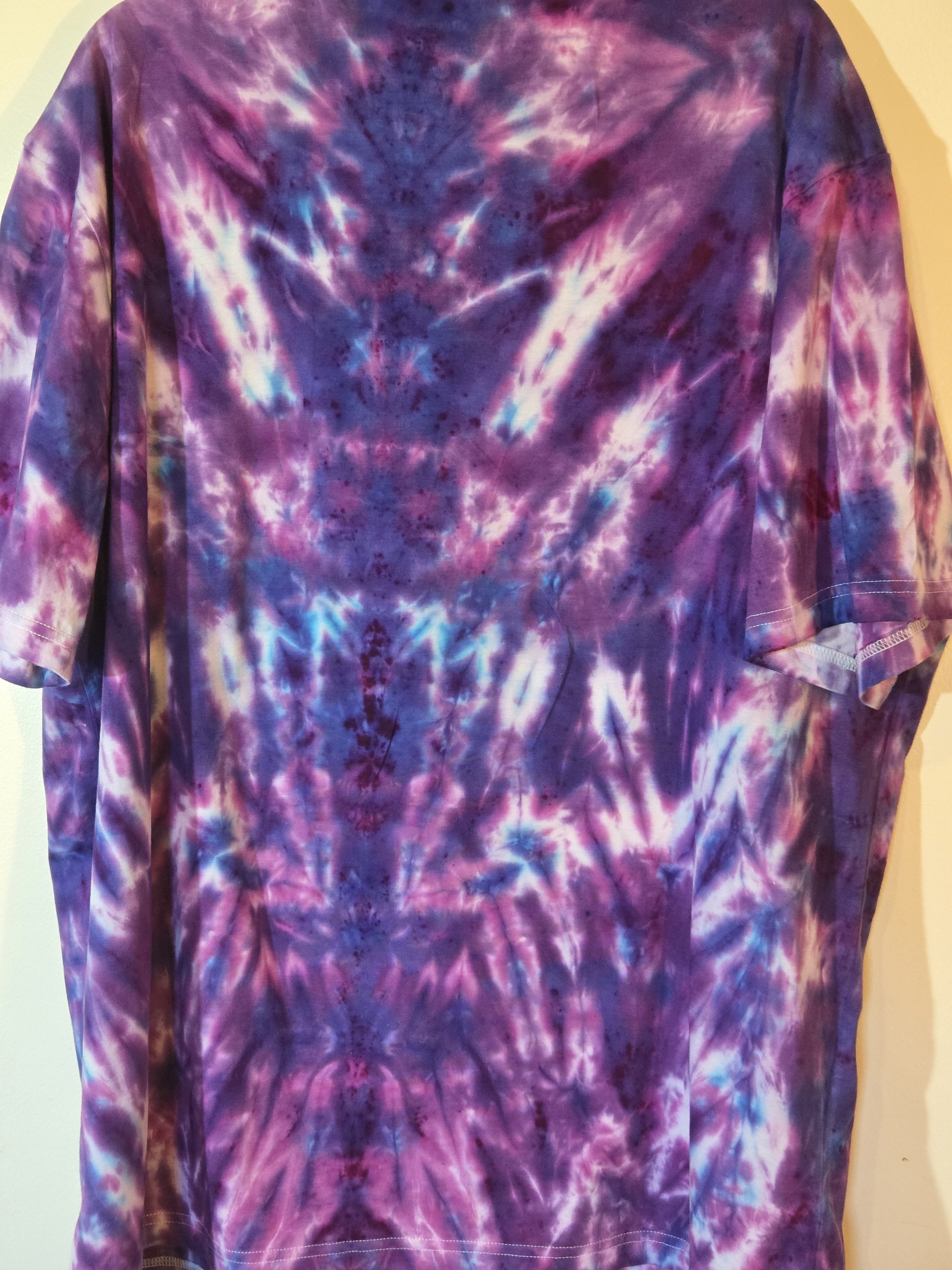 An adult XXL t-shirt featuring an intense red and burgundy tie-dye pattern that shapes a narrow fan at the neck and expands into a horizontal psychedelic design near the hem.