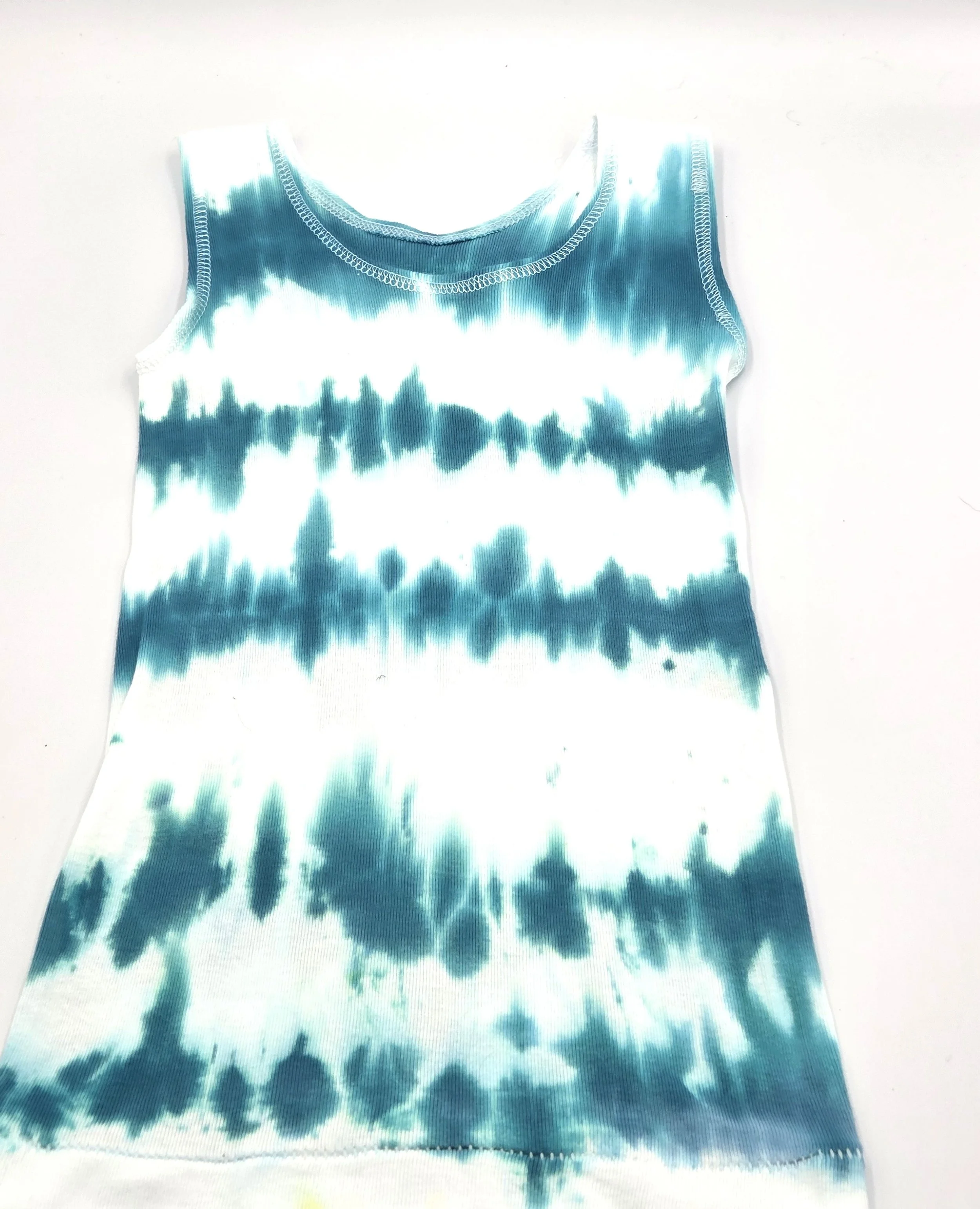 child's white singlet displaying a vertical tie-dye pattern of deep sea green wave lines.