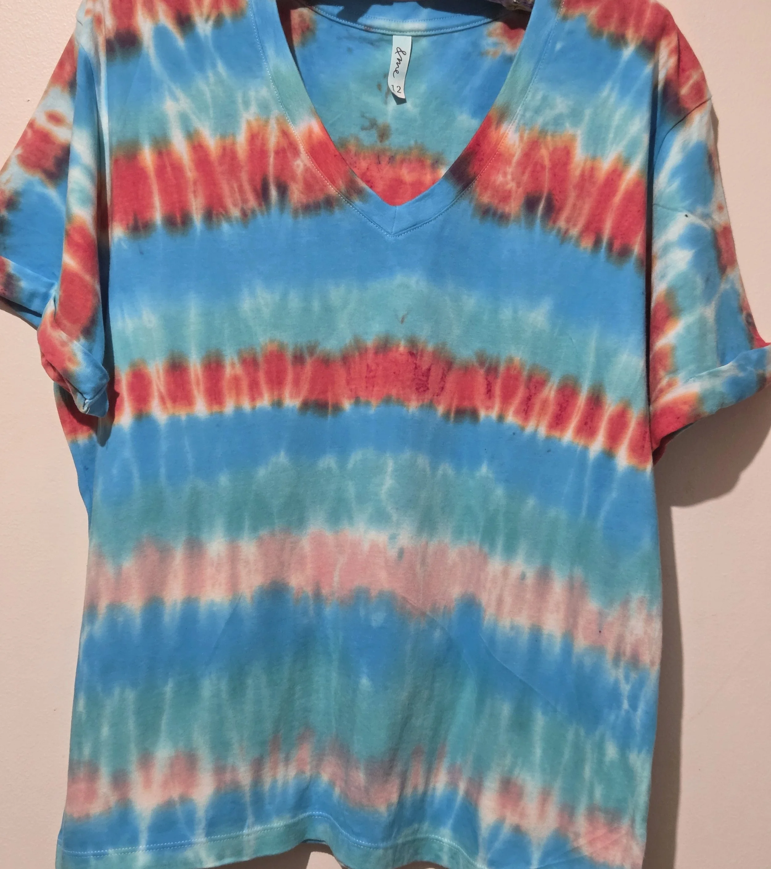 An adult size 12 women's V-neck cotton t-shirt with horizontal tie-dye stripes in coral, pink, turquoise, and Aegean green