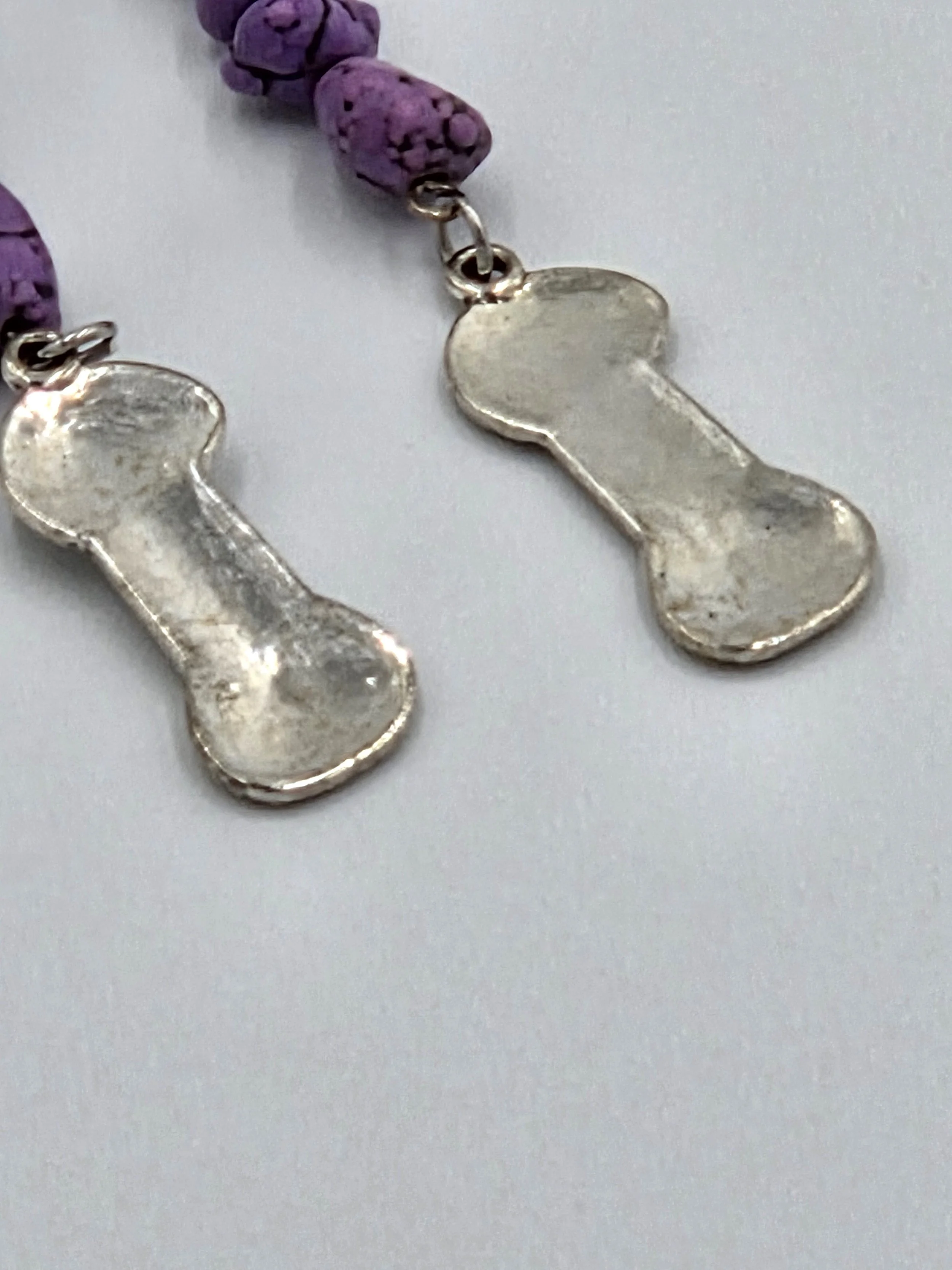 close up of Long silver earrings with purple stone nuggets and a silver yarn charm on silver hooks.