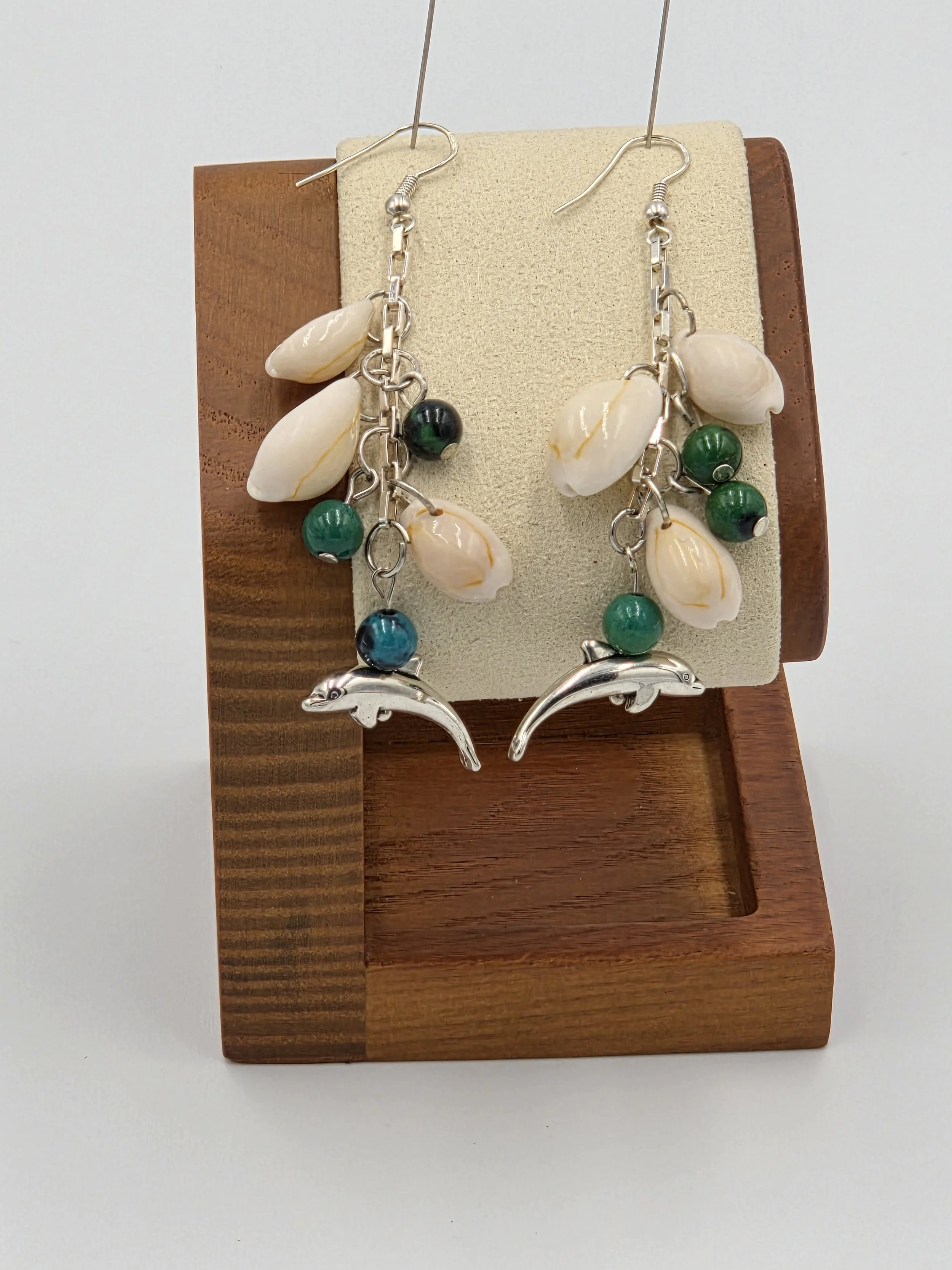 Long silver chain earrings with three cowrie shells, three blue-green gemstones, and dolphin charms.