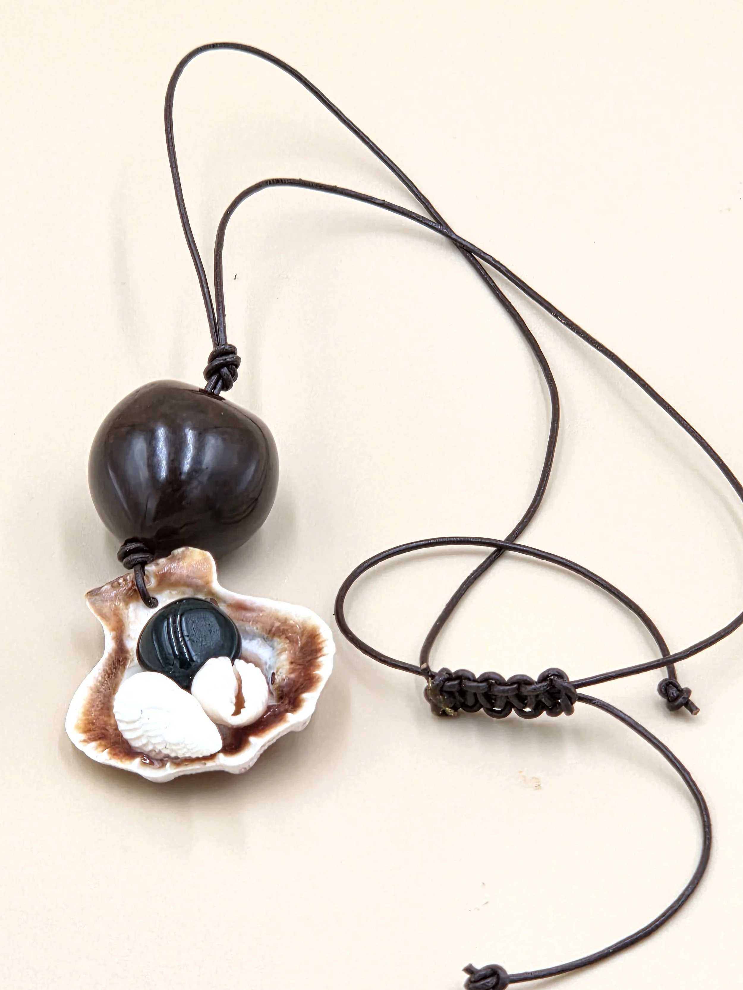 Australian handmade necklace with clam shell collage and seed pod on leather cord.