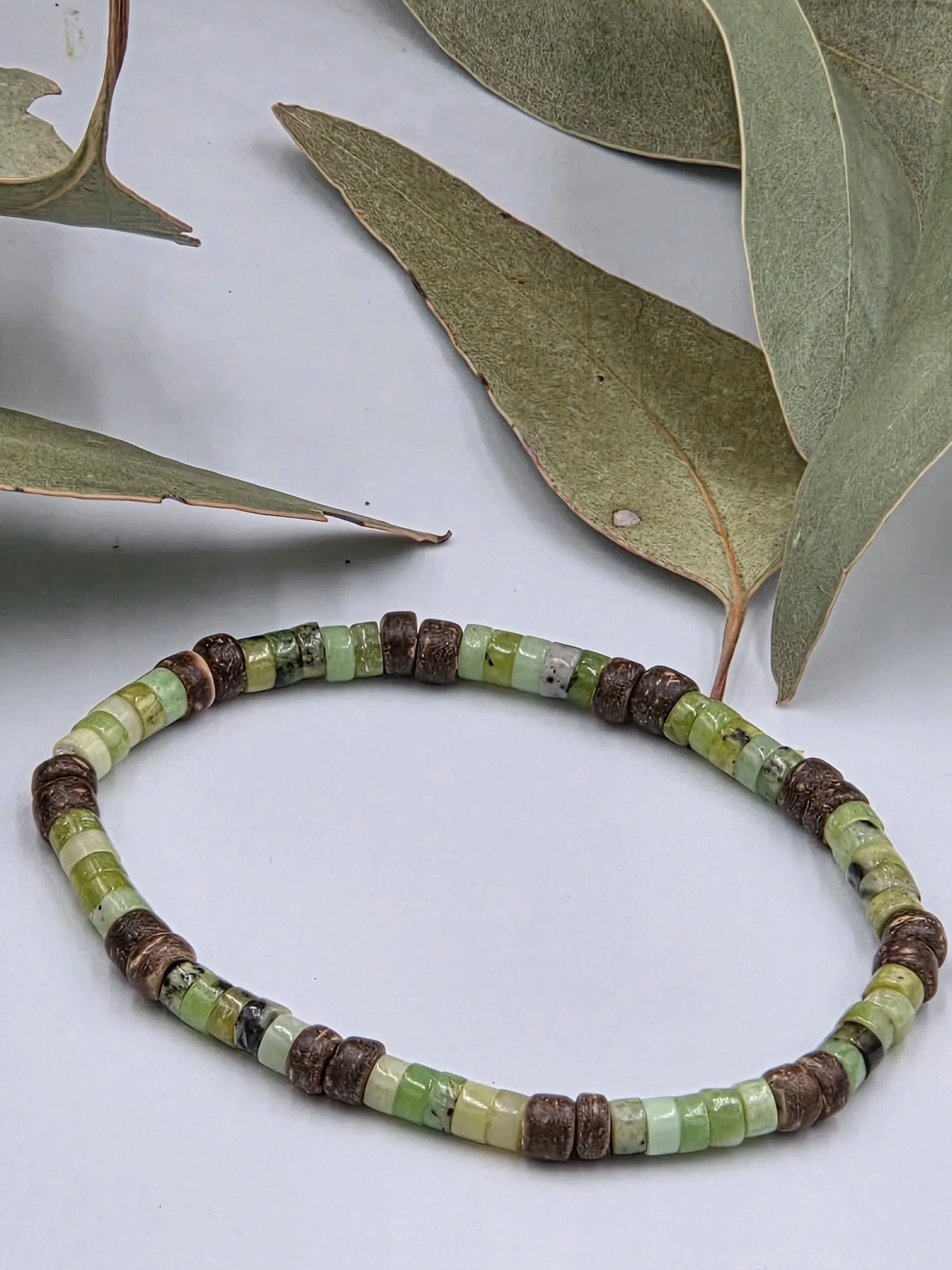 Very small green chrysoprase discs alternating in groups of five with pairs of brown coconut discs on a delicate elastic bracelet.