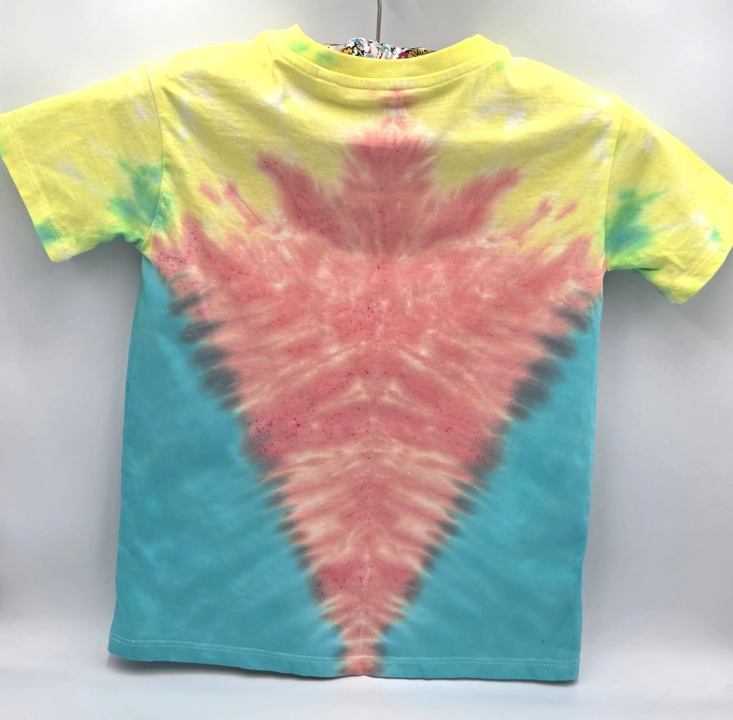back view A child's size 6 t-shirt with a half Y-fold tie-dye pattern featuring a central coral V-shape framed by teal sides and yellow shoulders.