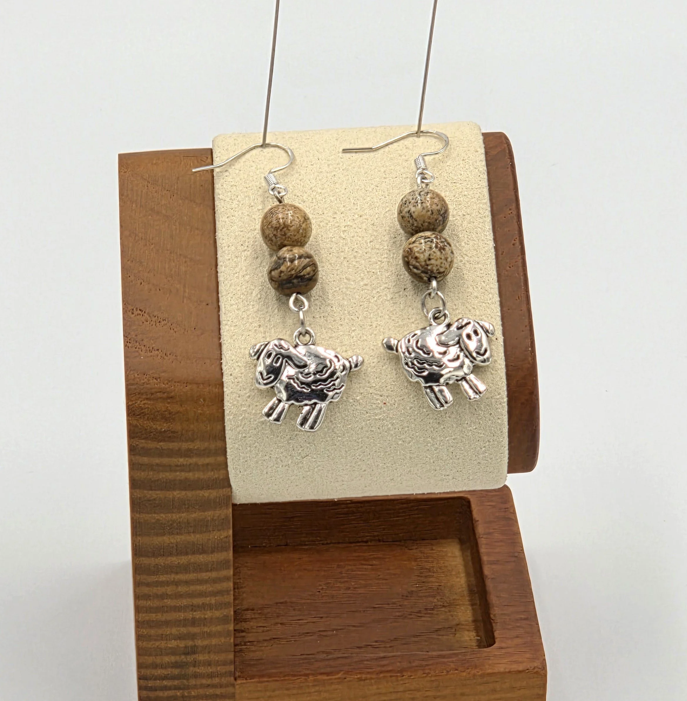 Silver sheep earrings with light brown patterned stone beads on silver hooks.