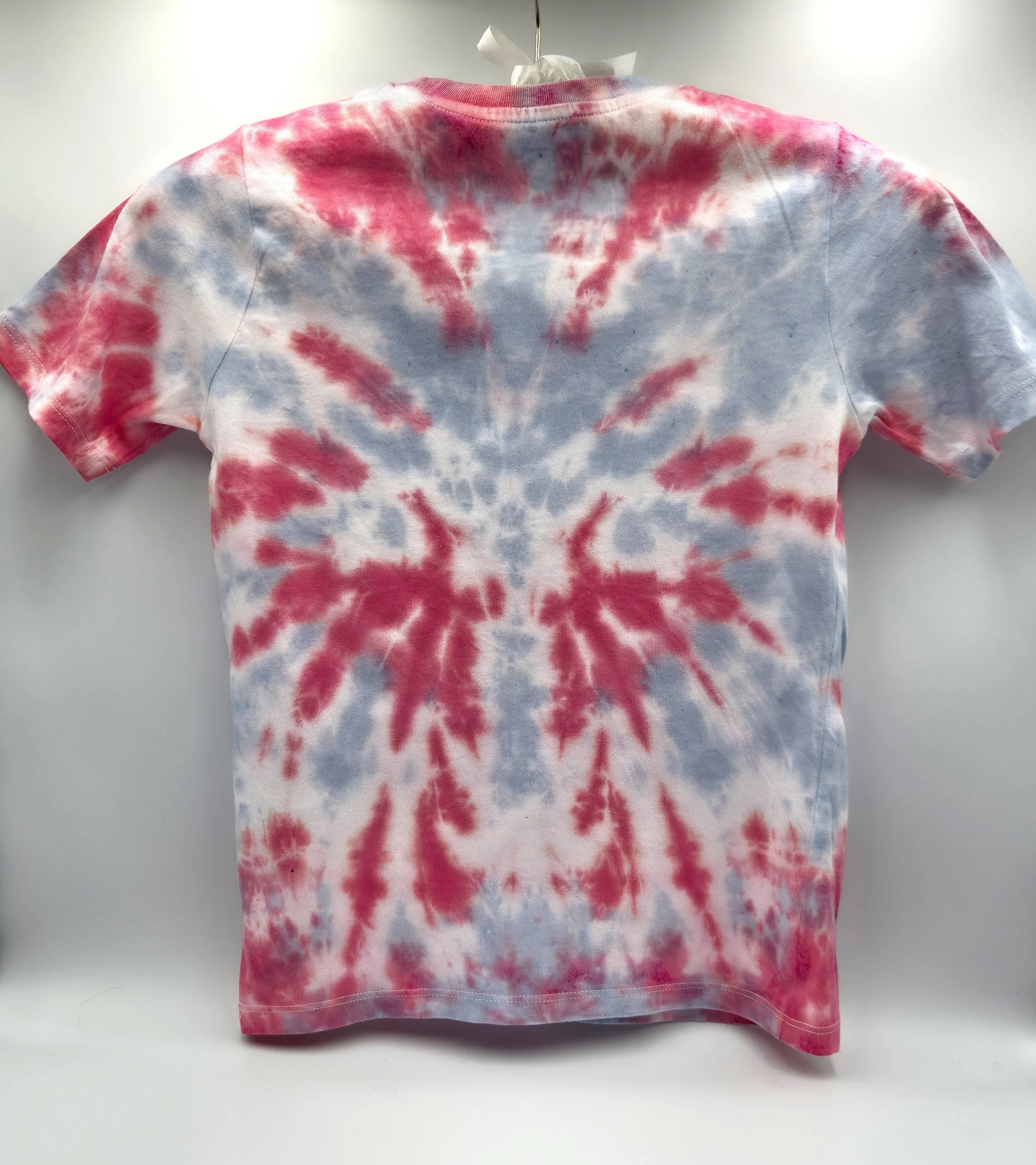 back view of a child's red t-shirt. A central pale grey tie-dye pattern resembles a large webbed flower.