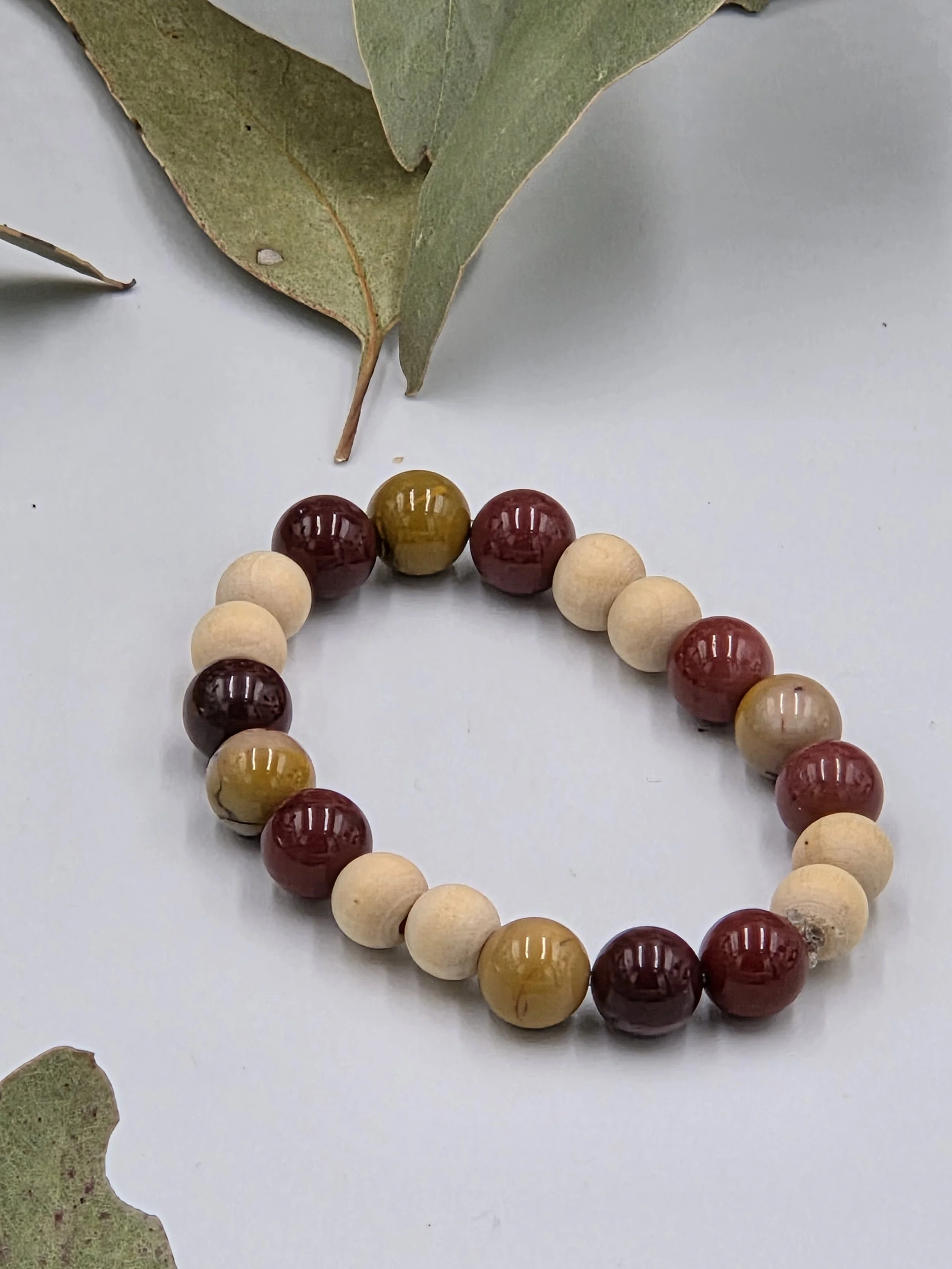 Earthy red and yellow Mookaite jasper beads alternating with small natural wood beads on an elastic bracelet.