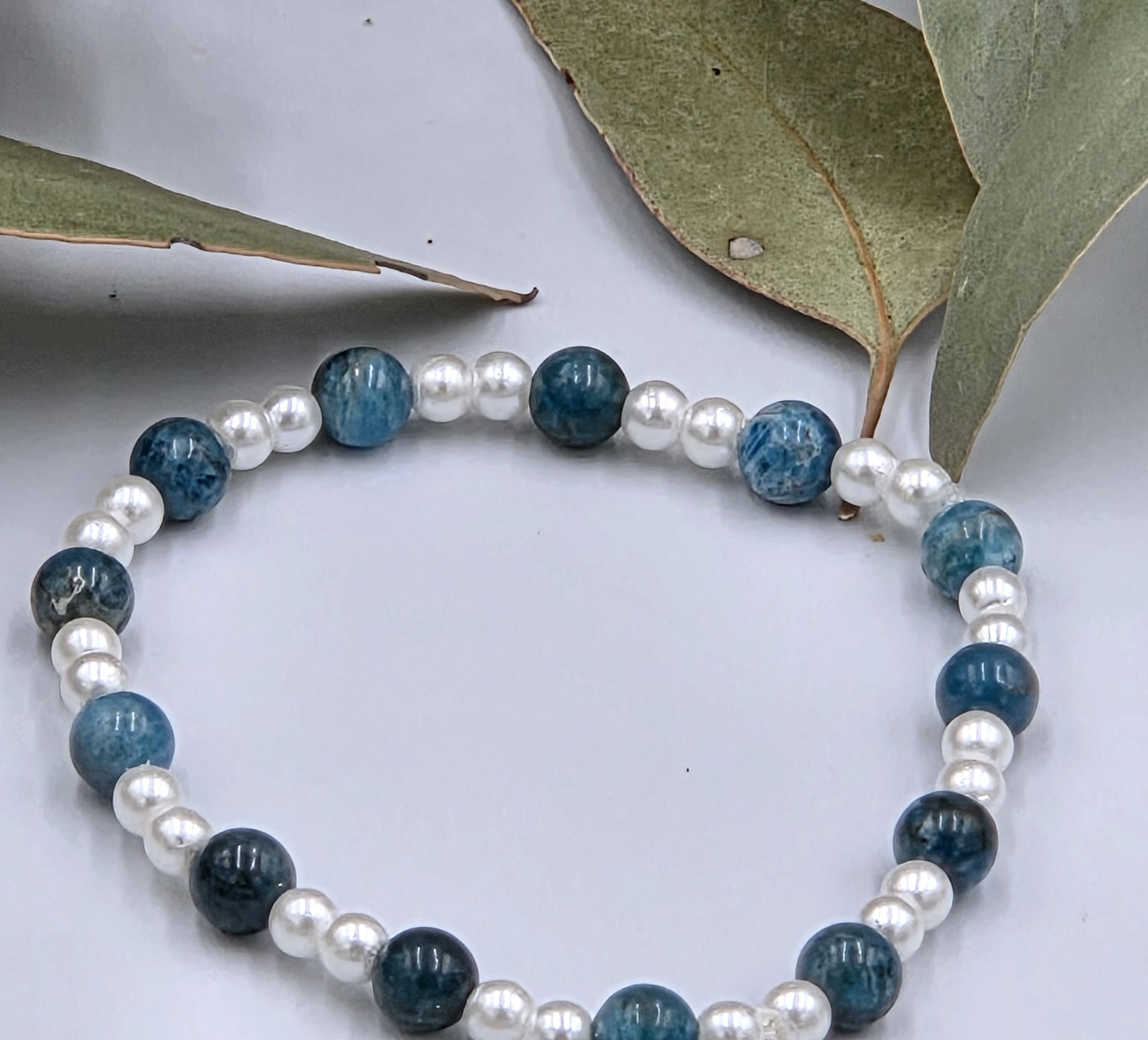 Deep blue Apatite beads alternating with small glossy white glass pearls on a delicate elastic bracelet.
