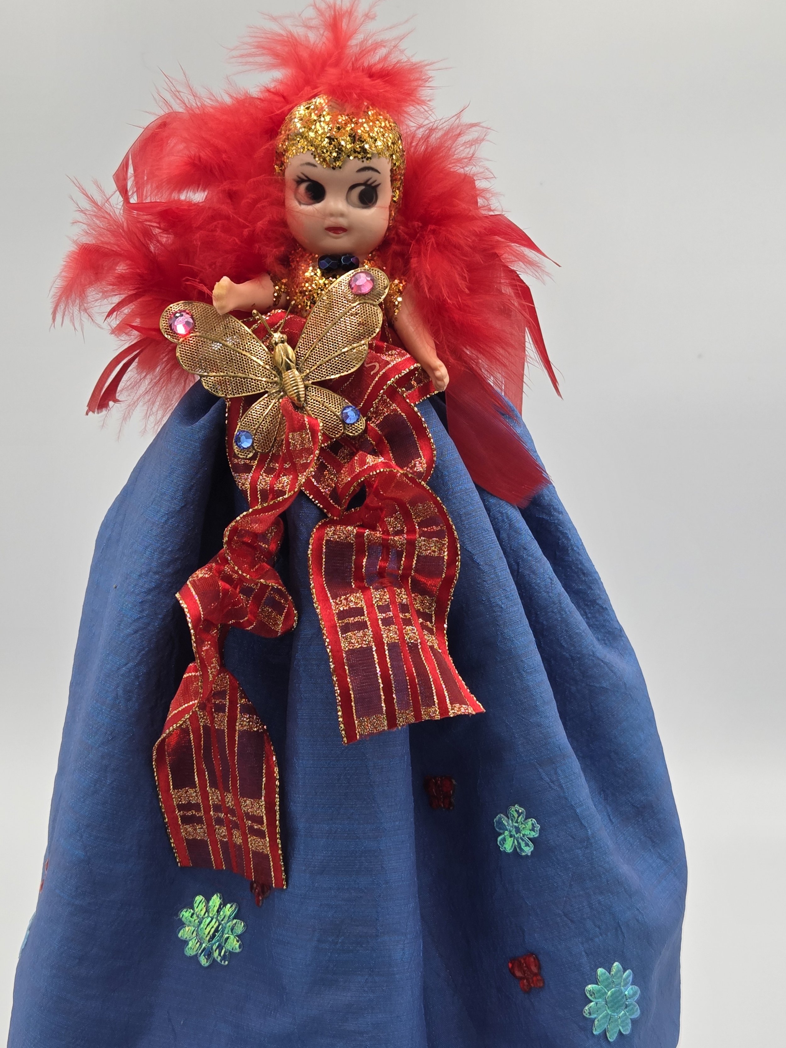 Antheia doll in sea-blue taffeta with golden butterfly and red feathers.