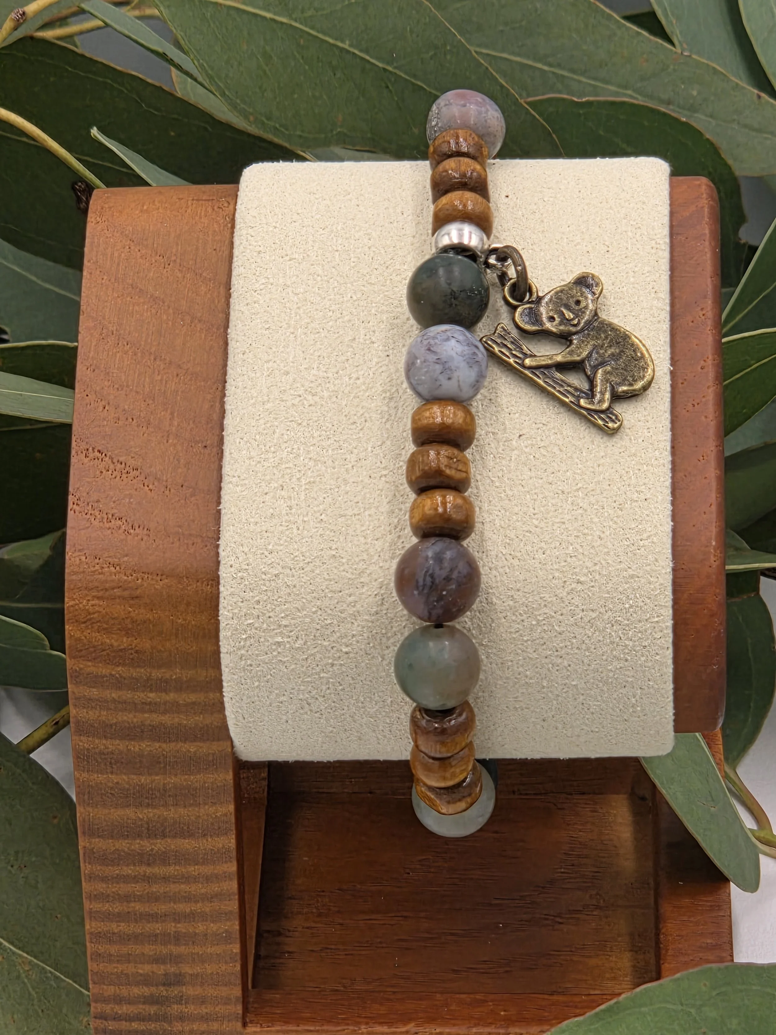 Close-up of Forest Dweller bracelet on wooden stand showing green and brown stone tones.