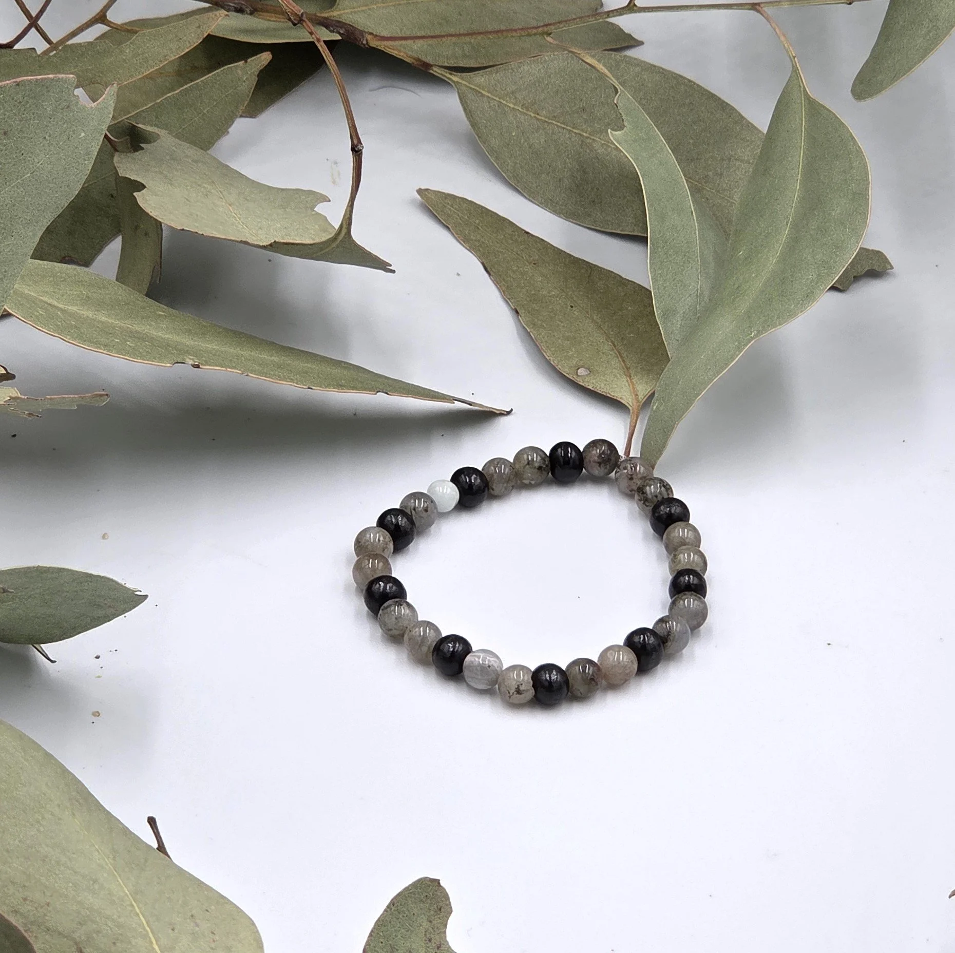 Grey Labradorite beads alternating in pairs with single black wood beads on an elastic bracelet.