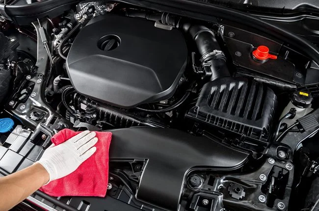 Hand cleaning car engine with a red cloth.