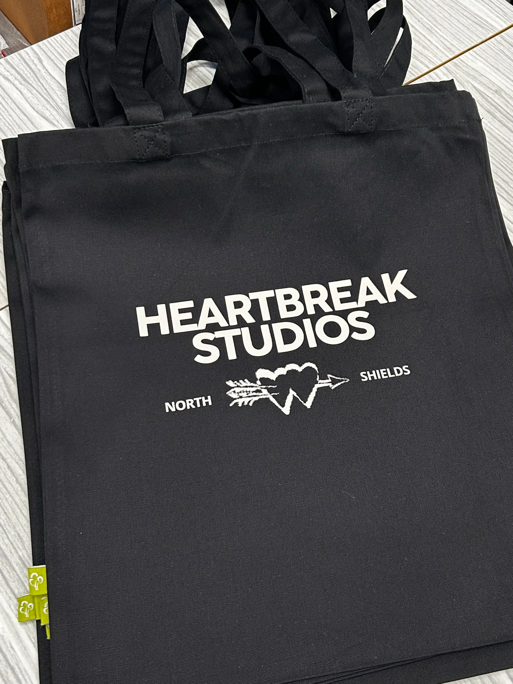 Black Earth Aware organic tote bag with Heartbreak Studios logo printed on the front with DTF transfer