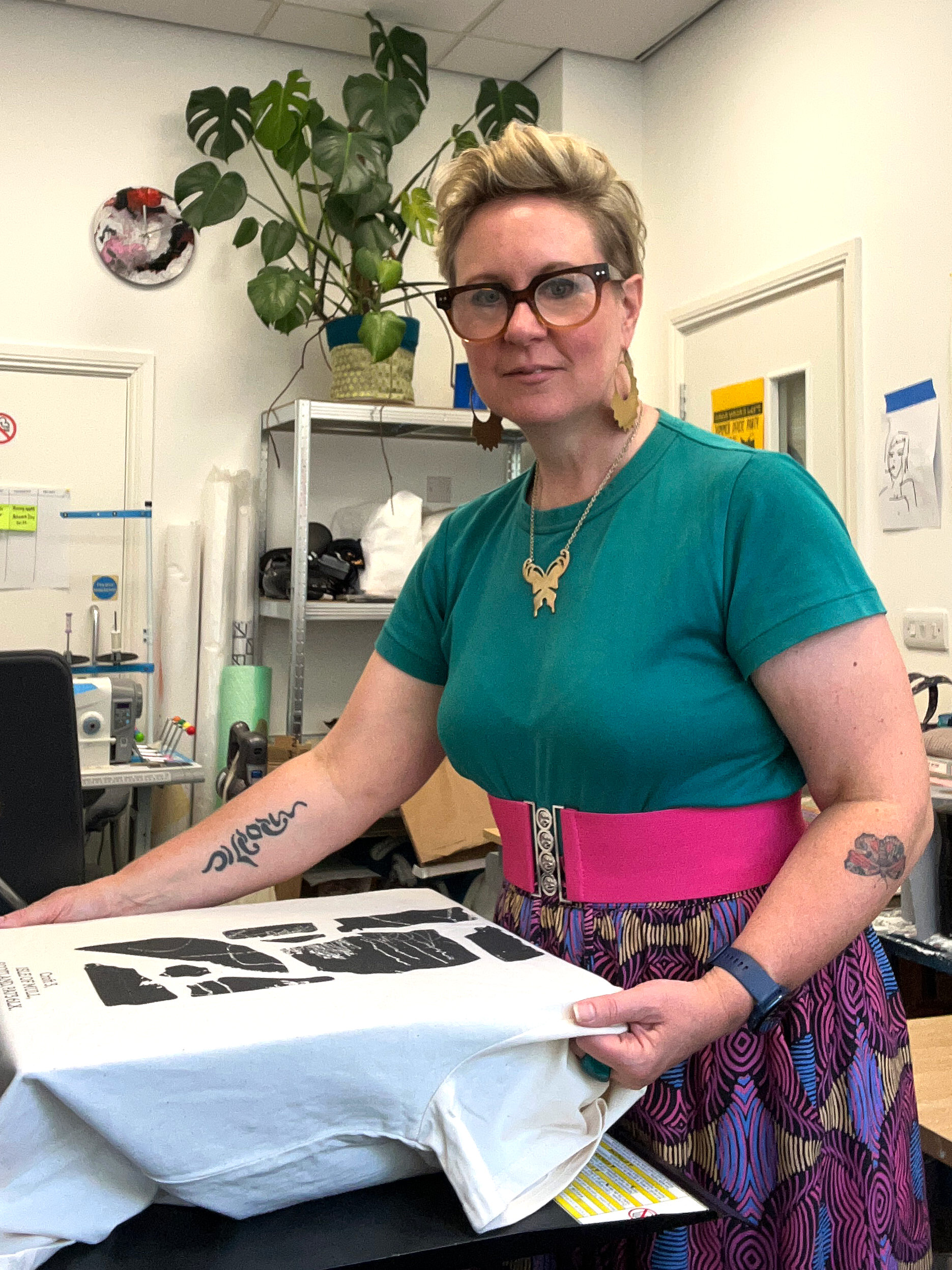 Beth Farmer, founder of Lyoness Press, a sustainable merch printing studio in North Shields, is checking a direct-to-garment print on a 100% organic cotton t-shirt on the platen of a DTG printer at the Lyoness Press studio.