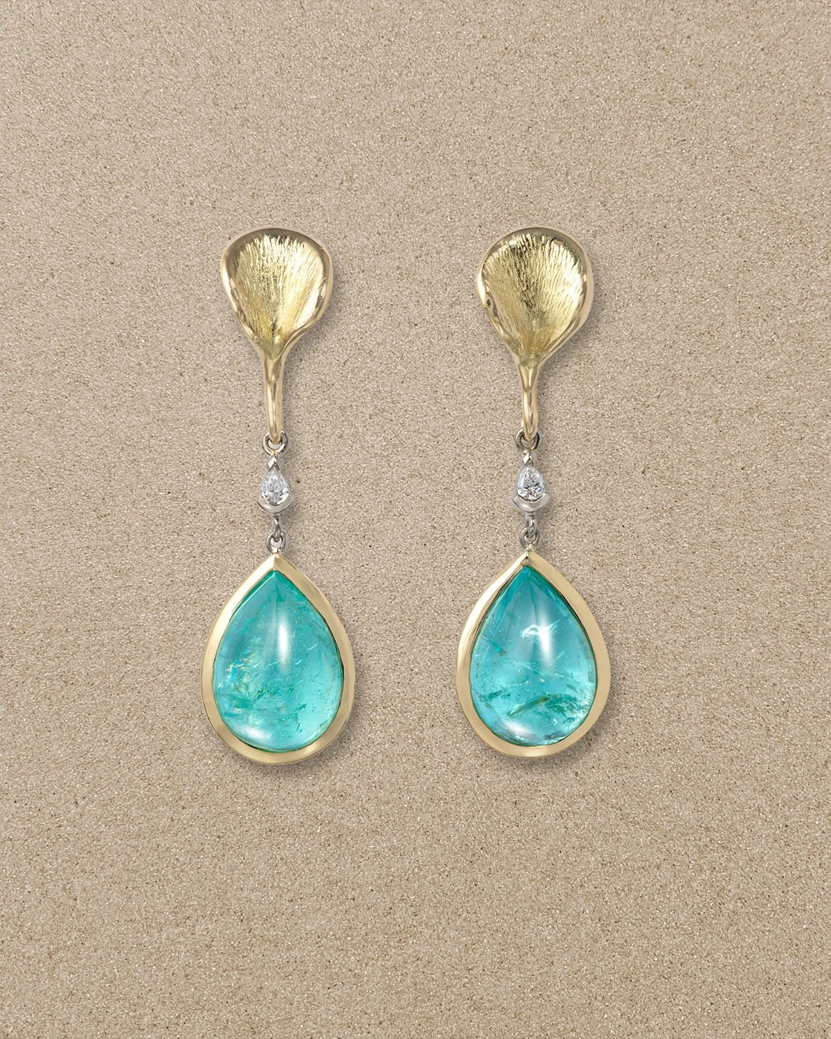 Pair of gold and silver earrings with turquoise teardrop stones and small diamonds.