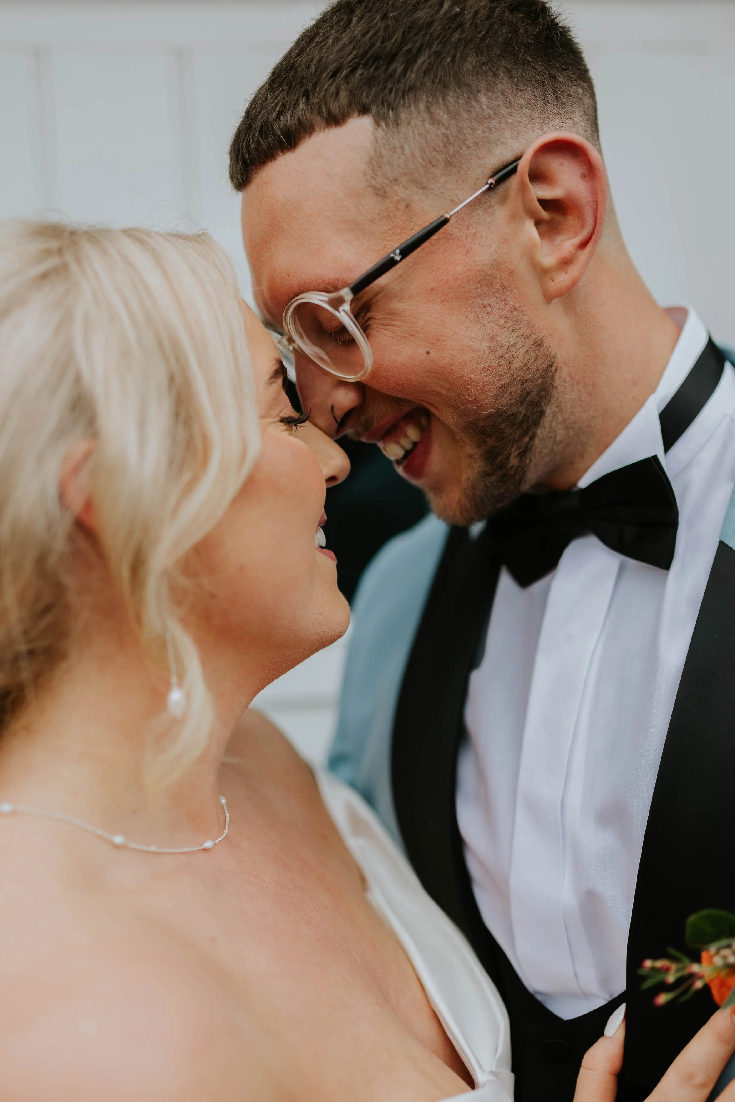 A close-up of a bride and groom sharing an intimate moment on their wedding day, with the groom smiling and the bride looking happy.