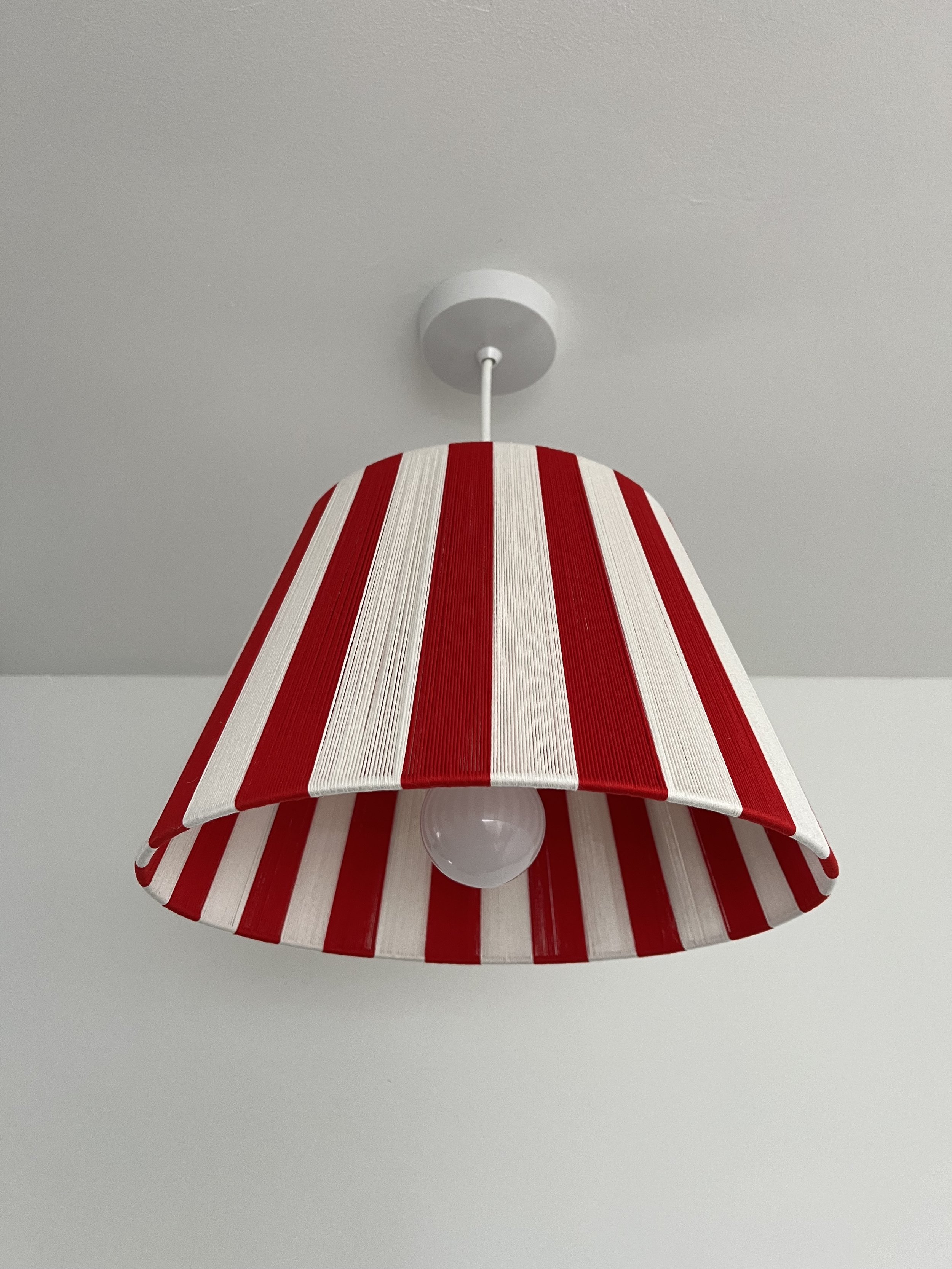 The Candy Cane Red Stripe Lampshade hanging from a cieling pendent