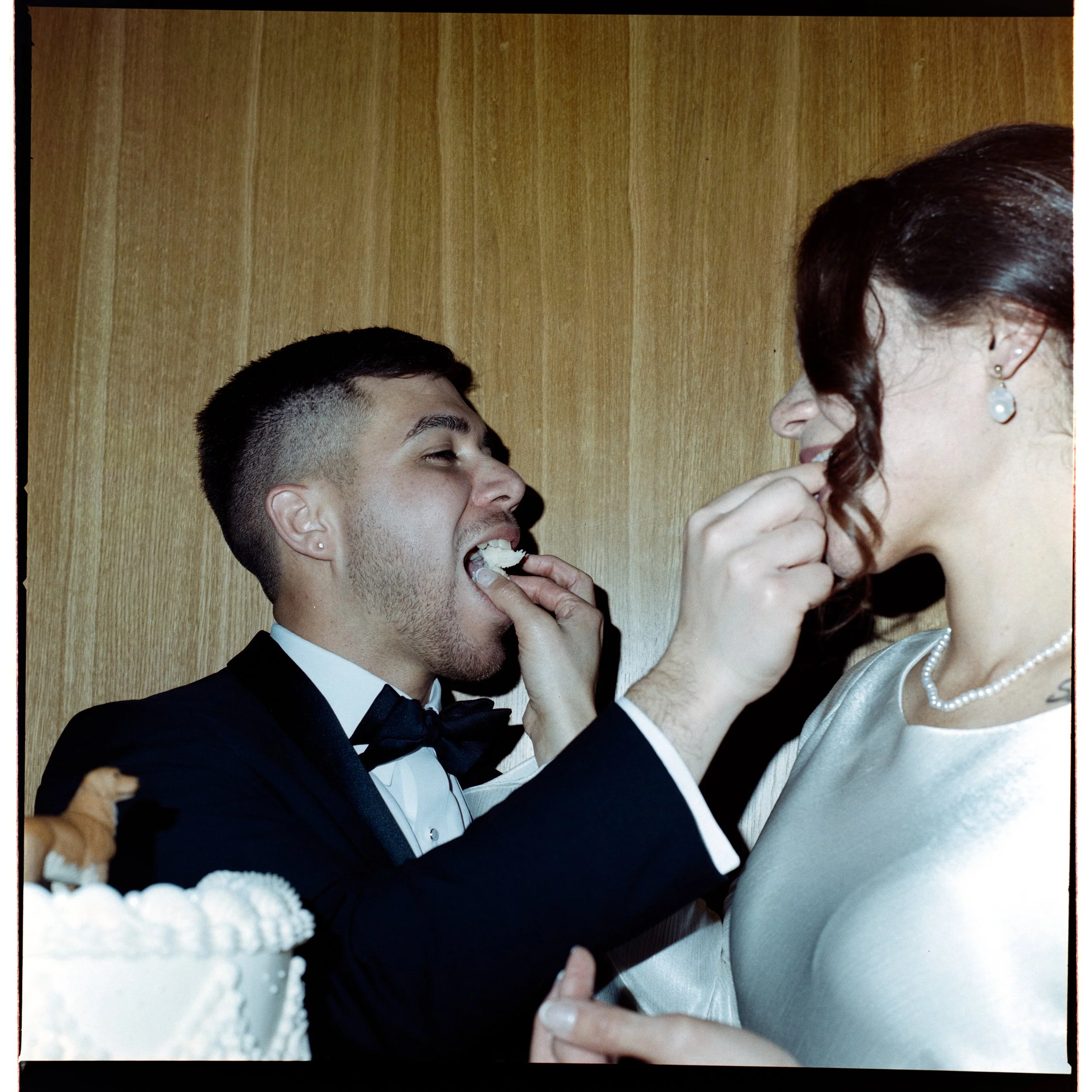 An unposed beautiful moment of a Puerto Rican bride and groom eating their wedding cake taken on 120 medium format Kodak film