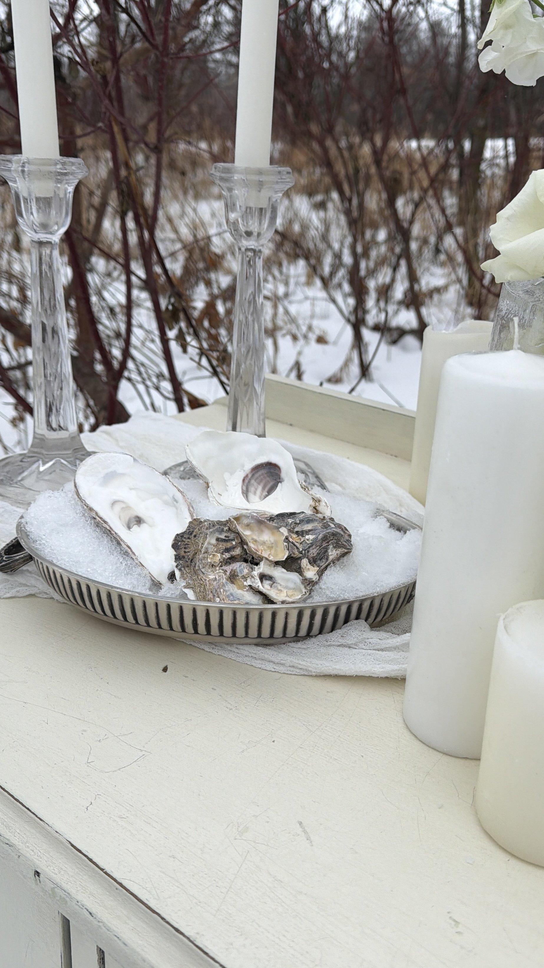 Close-up of a romantic winter wedding hutch with candles, oysters, and snowy accents in a rustic outdoor setting located in Edmonton Alberta