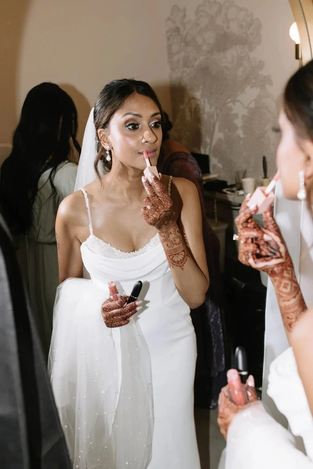 A candid moment of the bride touching up her makeup on her wedding day.