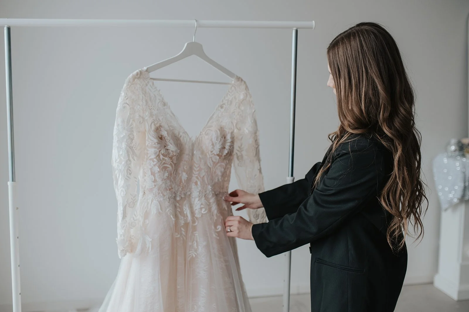 Photo of wedding coordinator helping with brides dress on her morning of