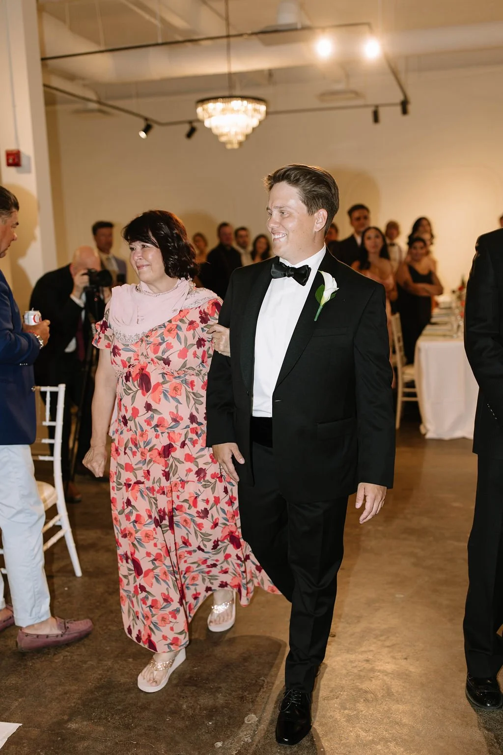 A candid moment of the groom walking down the aisle with his mom during the wedding ceremony.