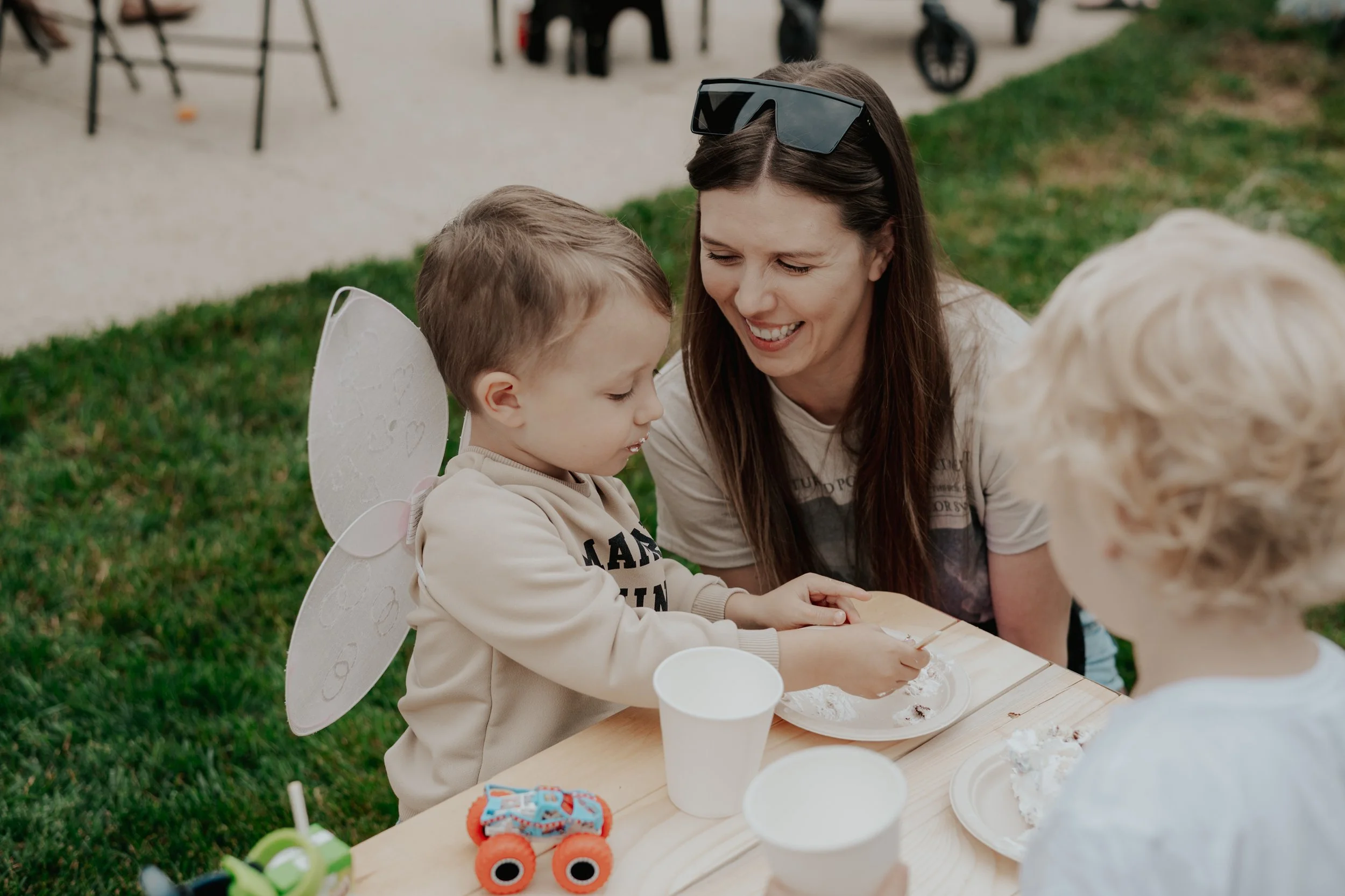 Photograph of child eating cake at kids birthday party and parent smiling