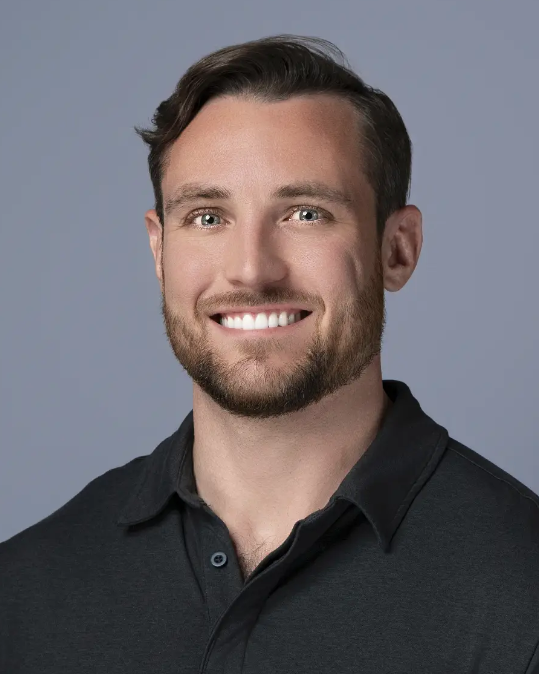 Man in a black shirt standing in a tire warehouse, surrounded by stacked tires.