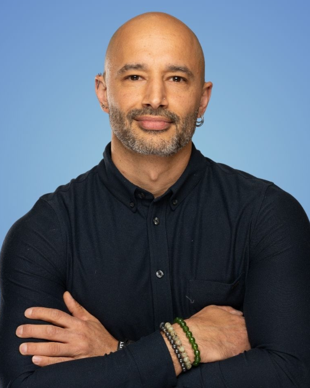 Man in a black shirt standing in a tire warehouse, surrounded by stacked tires.