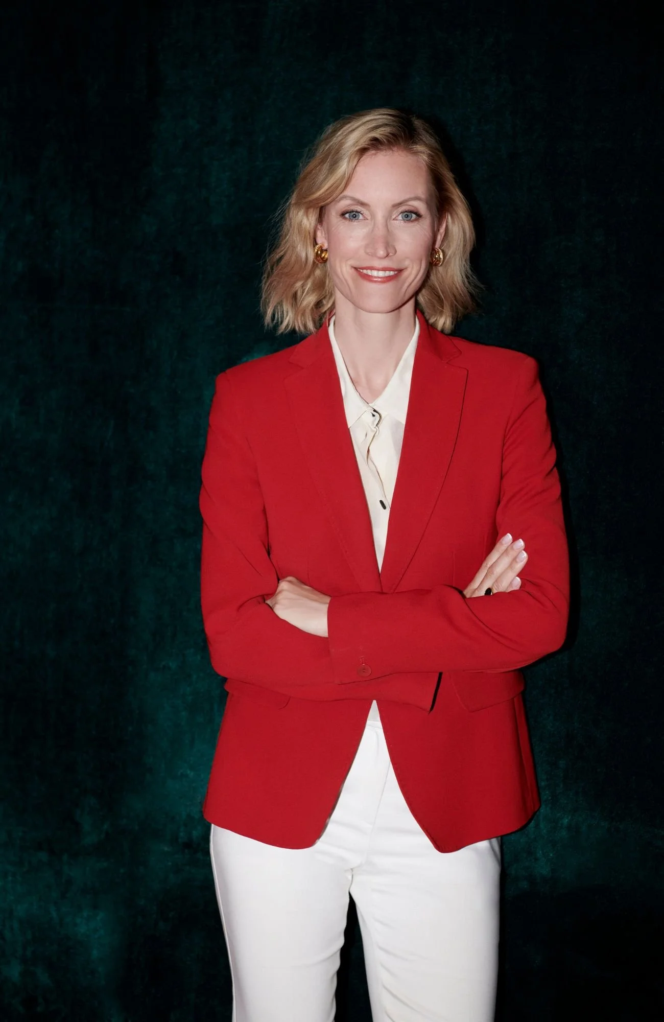 A holistic health coach named Heidi Hauer, elegantly dressed in a red blazer and white pants.