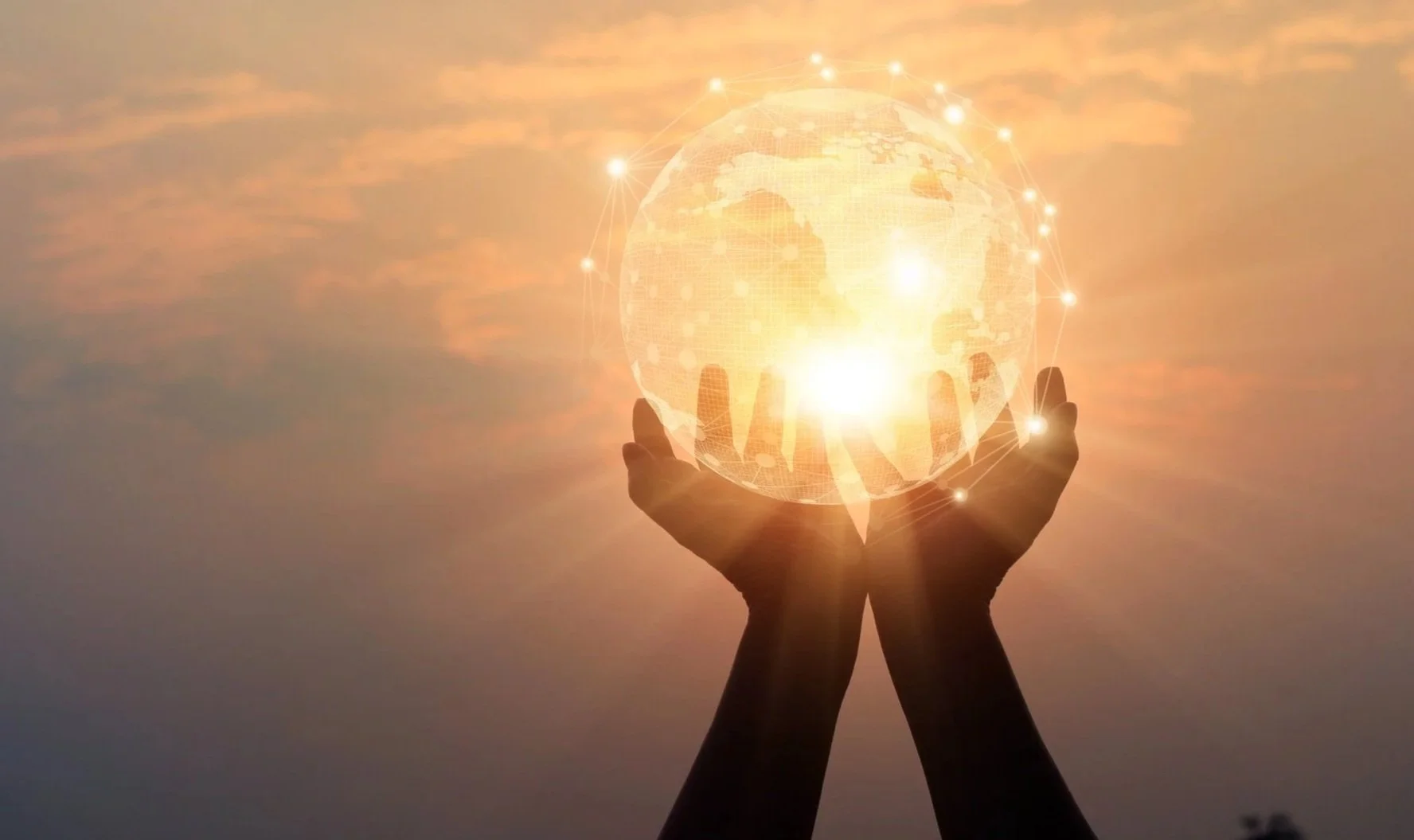 Two hands holding a glowing, digital globe with city map and connecting lines, against a sunset sky.