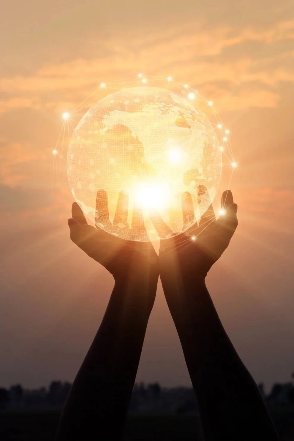 Two hands holding a glowing, digital globe against a sunset sky.