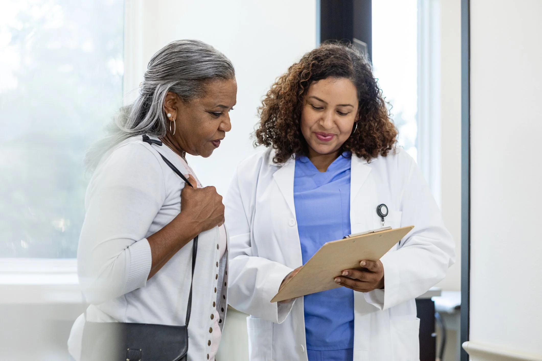 Healthcare provider and an older adult patient reviewing information on a clipboard together.