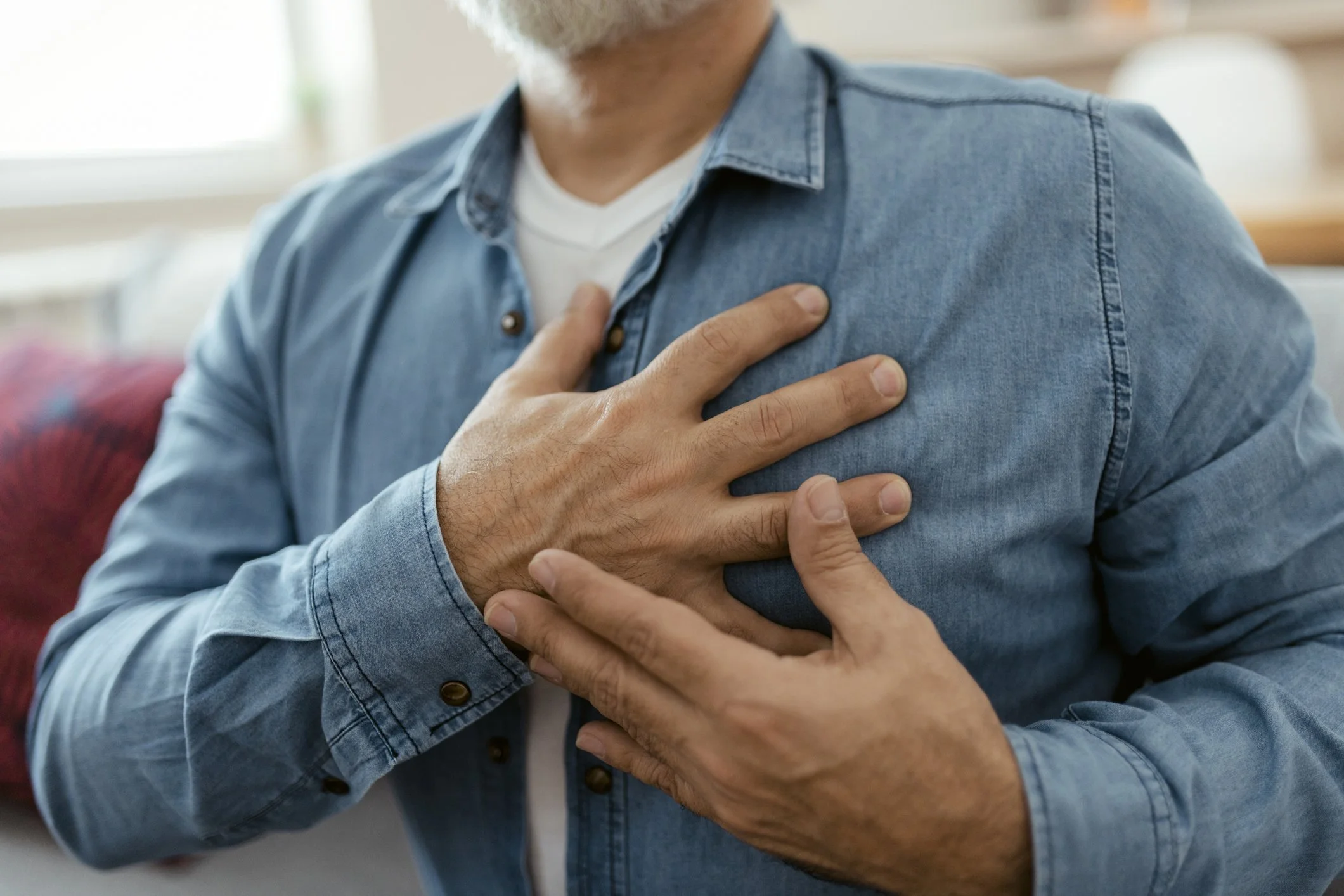 Man holding his chest to represent chest pain as a possible symptom of lung cancer.