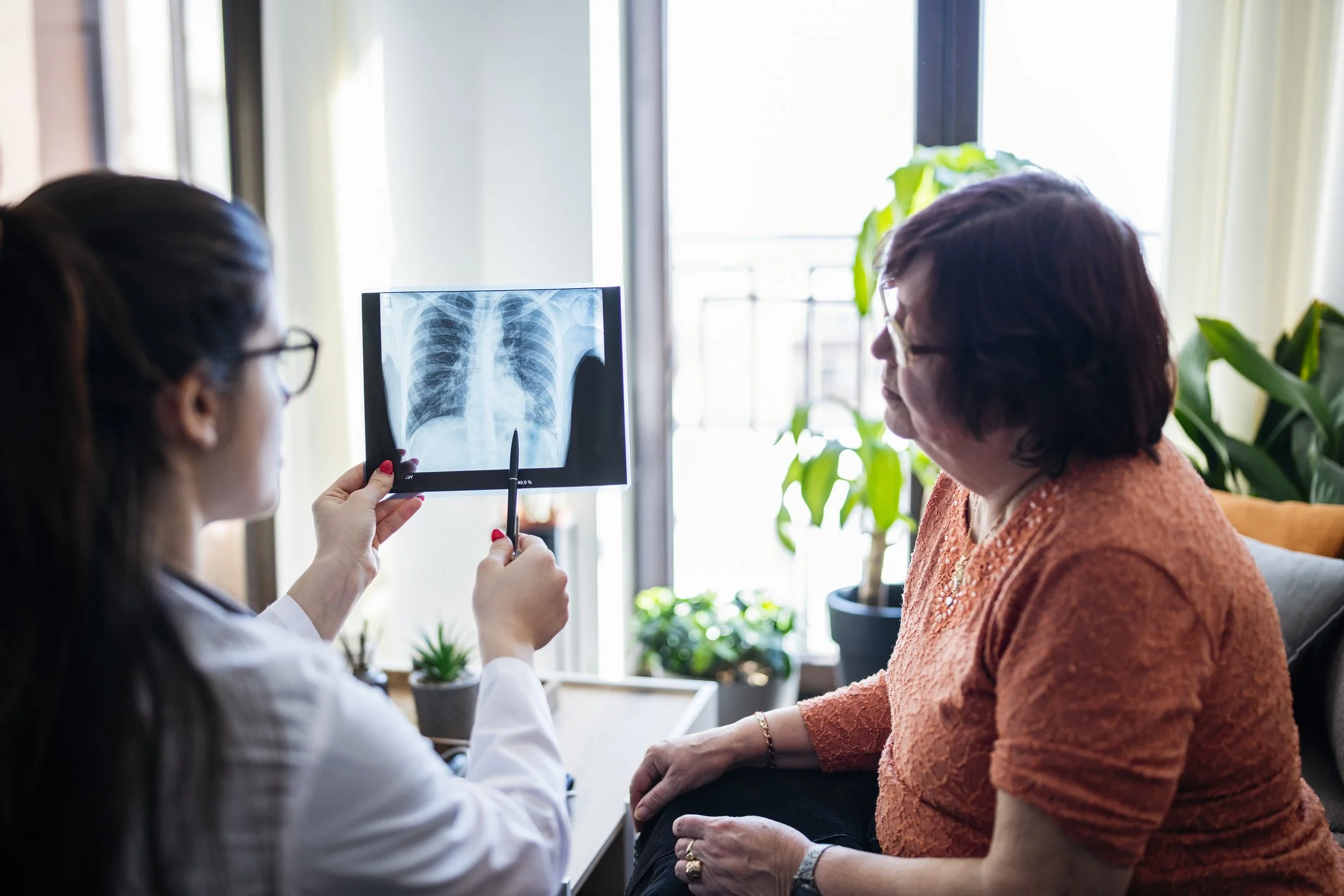 Clinician reviewing a chest X-ray with a patient, illustrating how imaging and earlier lung cancer detection support clearer clinical decisions.