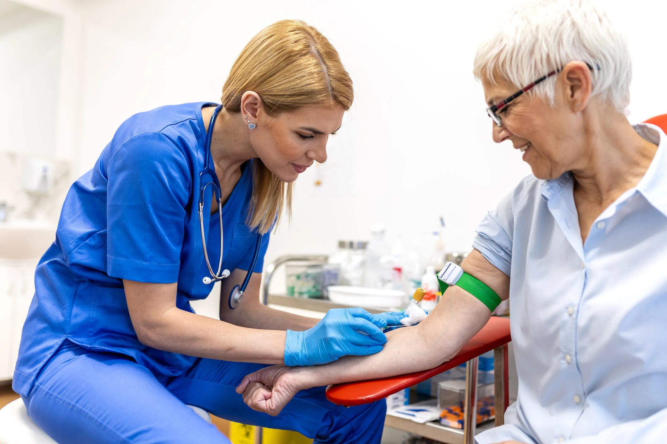 Friendly phlebotomist collecting a blood sample from a patient — the CIZ1B biomarker blood test requires only a simple blood draw