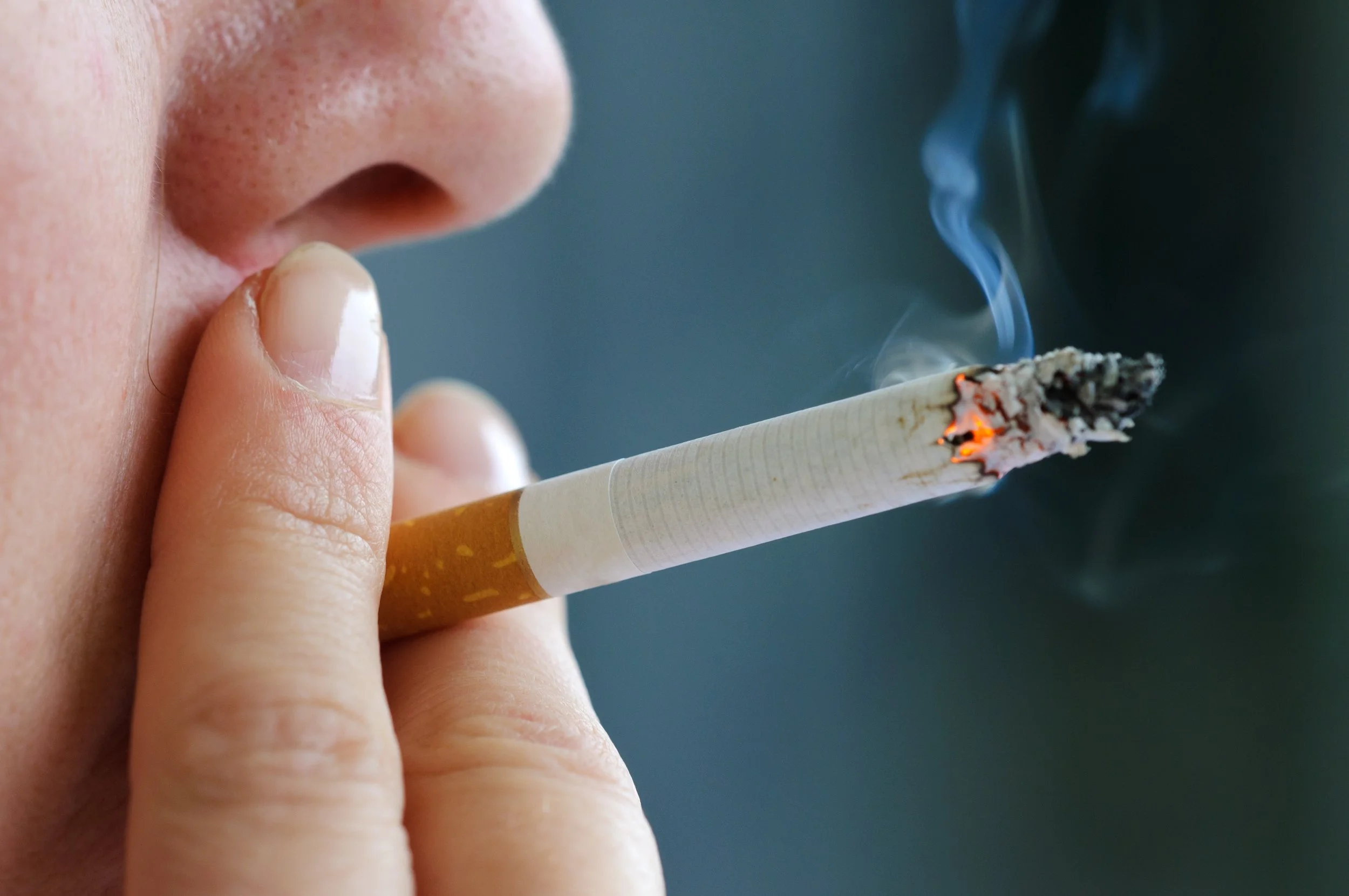 Close-up of a person smoking a cigarette, illustrating tobacco smoke as a leading risk factor for lung cancer.
