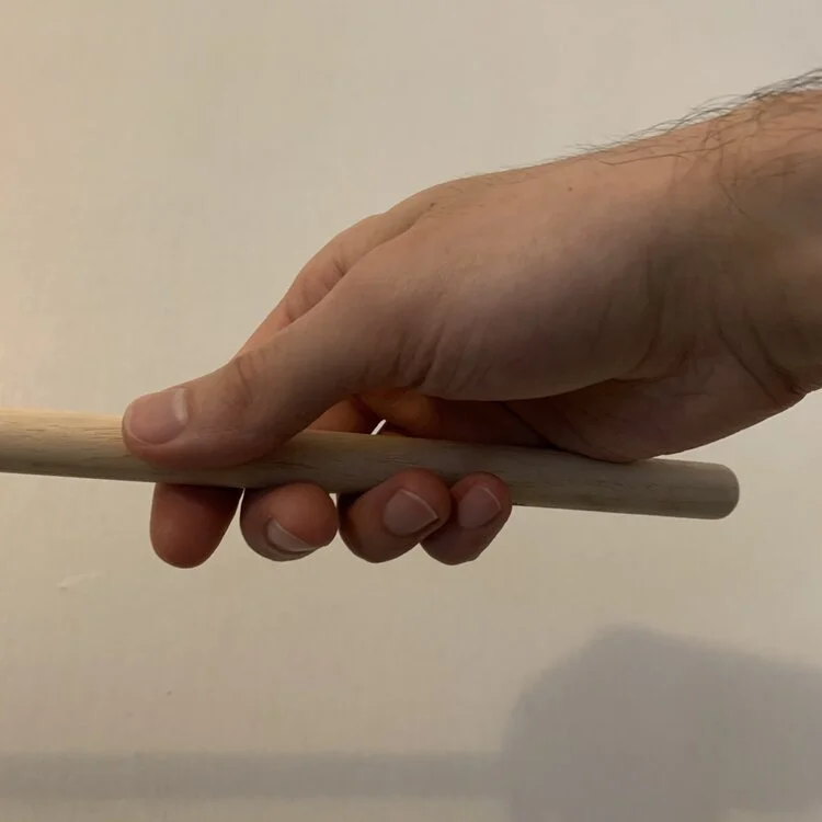 An underside view of a hand curved around a drum stick.