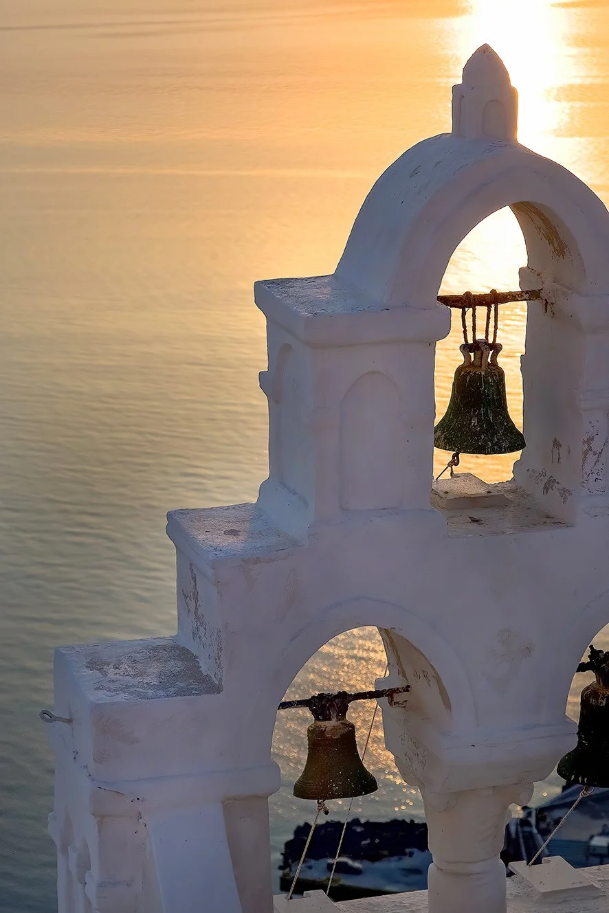 Crowds and photographers watching the famous Santorini sunset from Oia Castle ruins with fiery colors reflecting on the caldera.