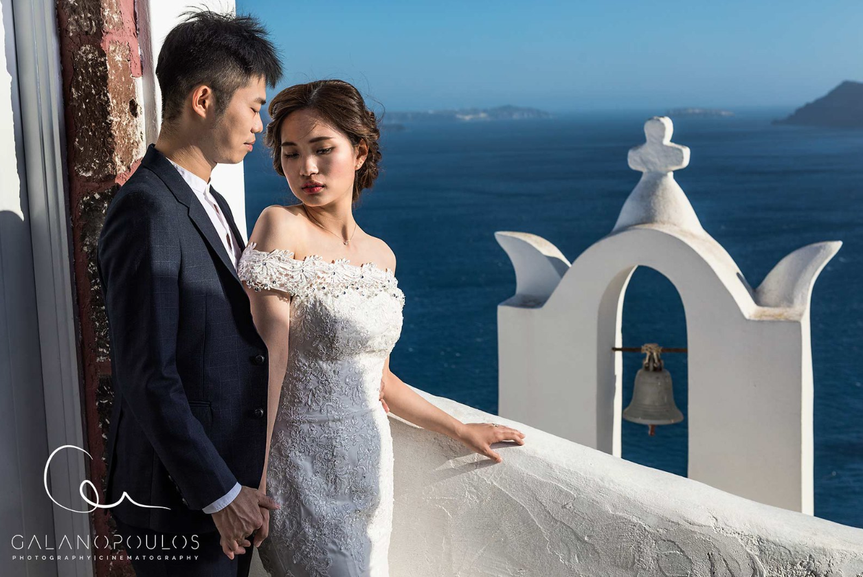Couple proposing at Oia blue domes at sunset, joyful Proposal moment framed by iconic architecture and warm light.
